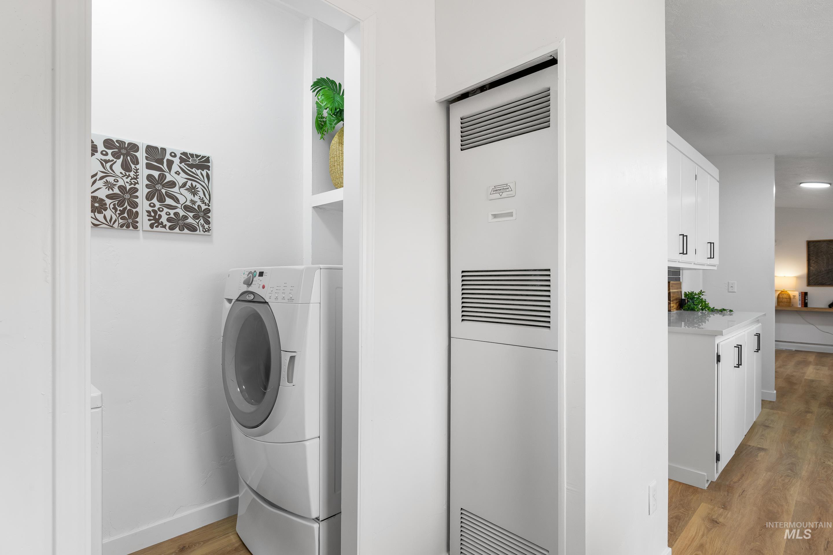 Laundry area with a heating unit, light wood finished floors, and washer / dryer