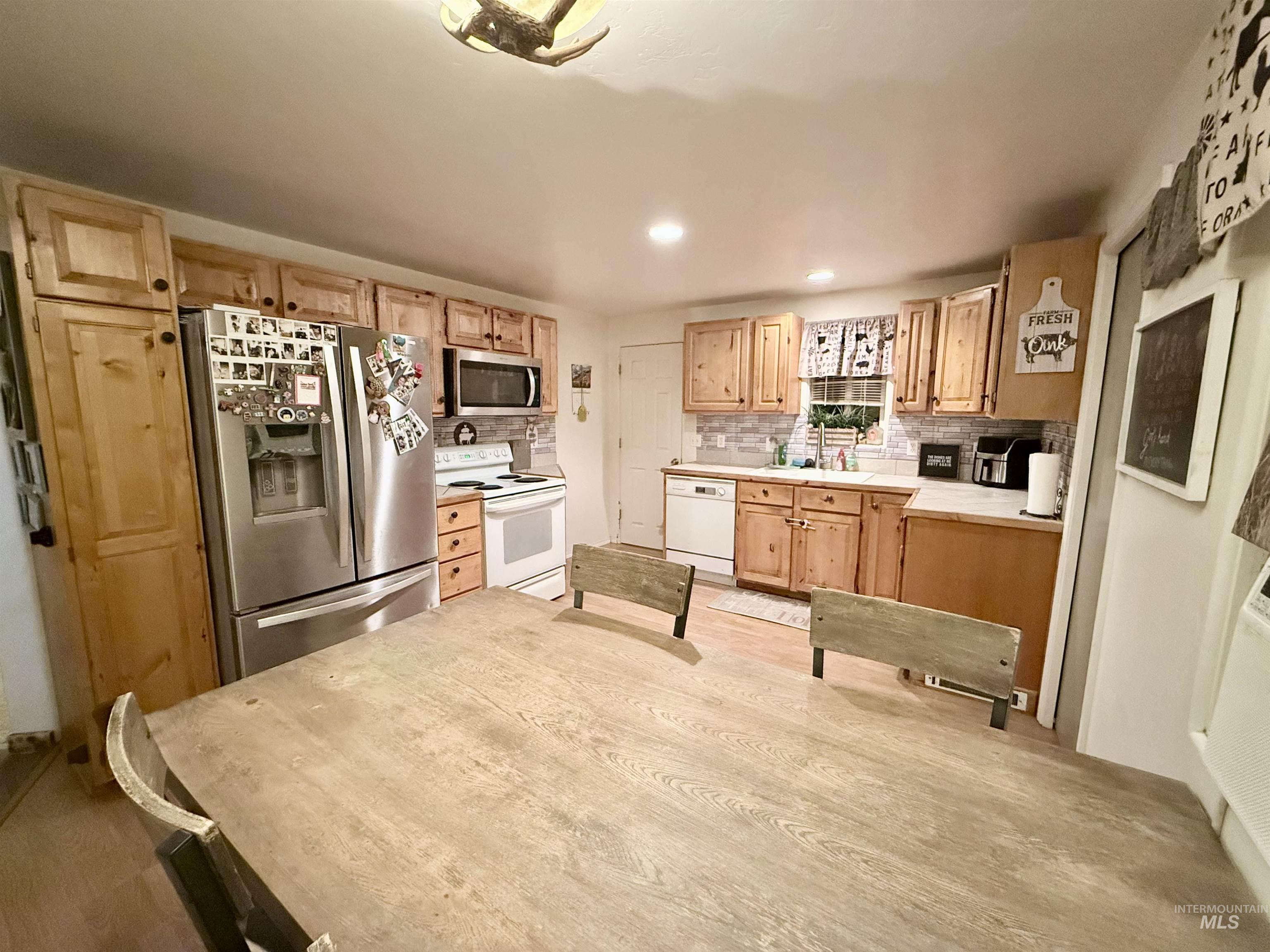 Kitchen featuring appliances with stainless steel finishes, light countertops, decorative backsplash, light wood finished floors, and recessed lighting