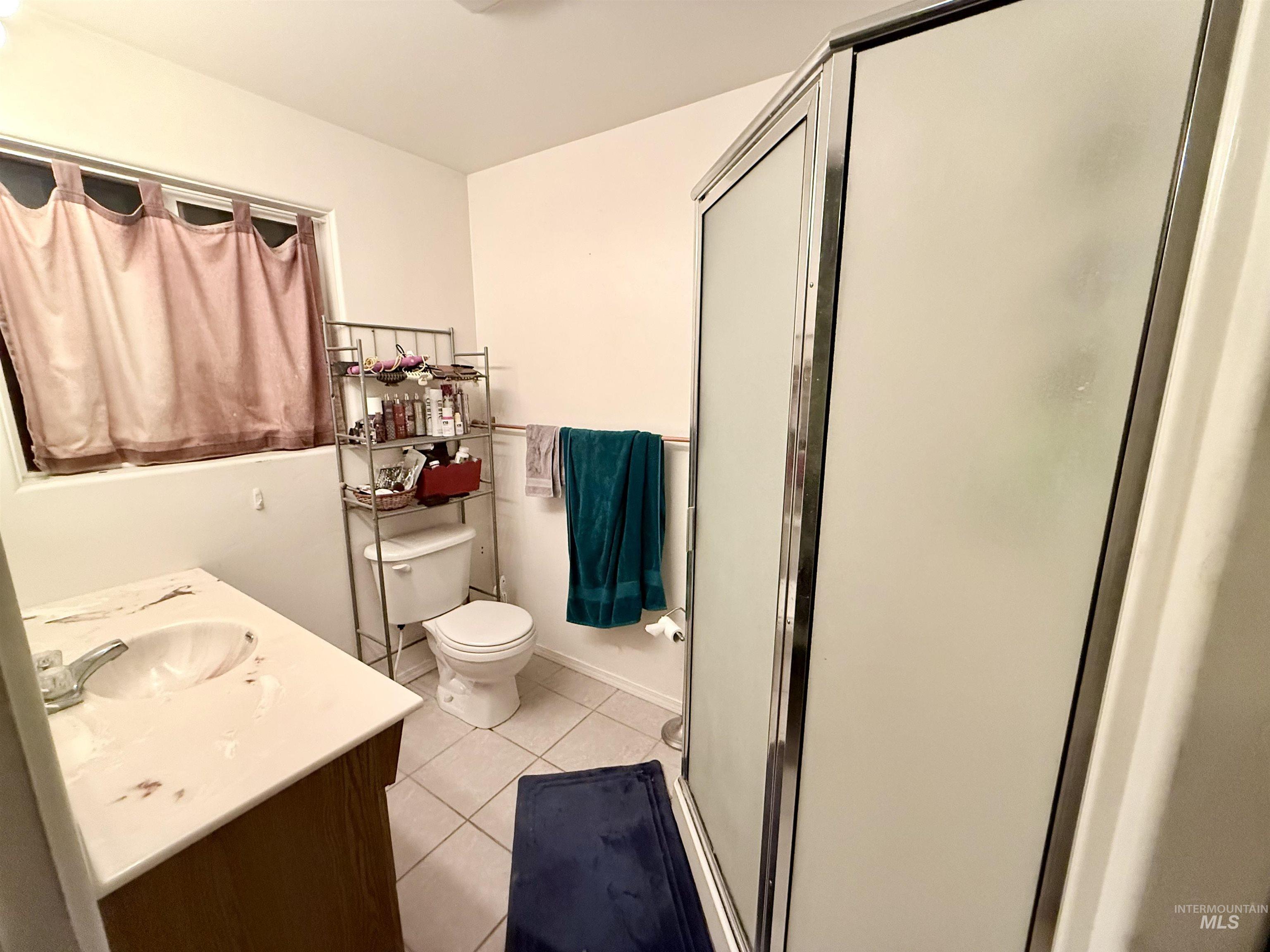 Bathroom featuring light tile patterned floors, vanity, and a shower stall