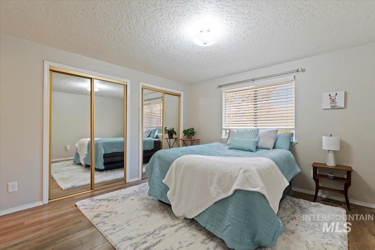Bedroom featuring two closets, a textured ceiling, and wood finished floors