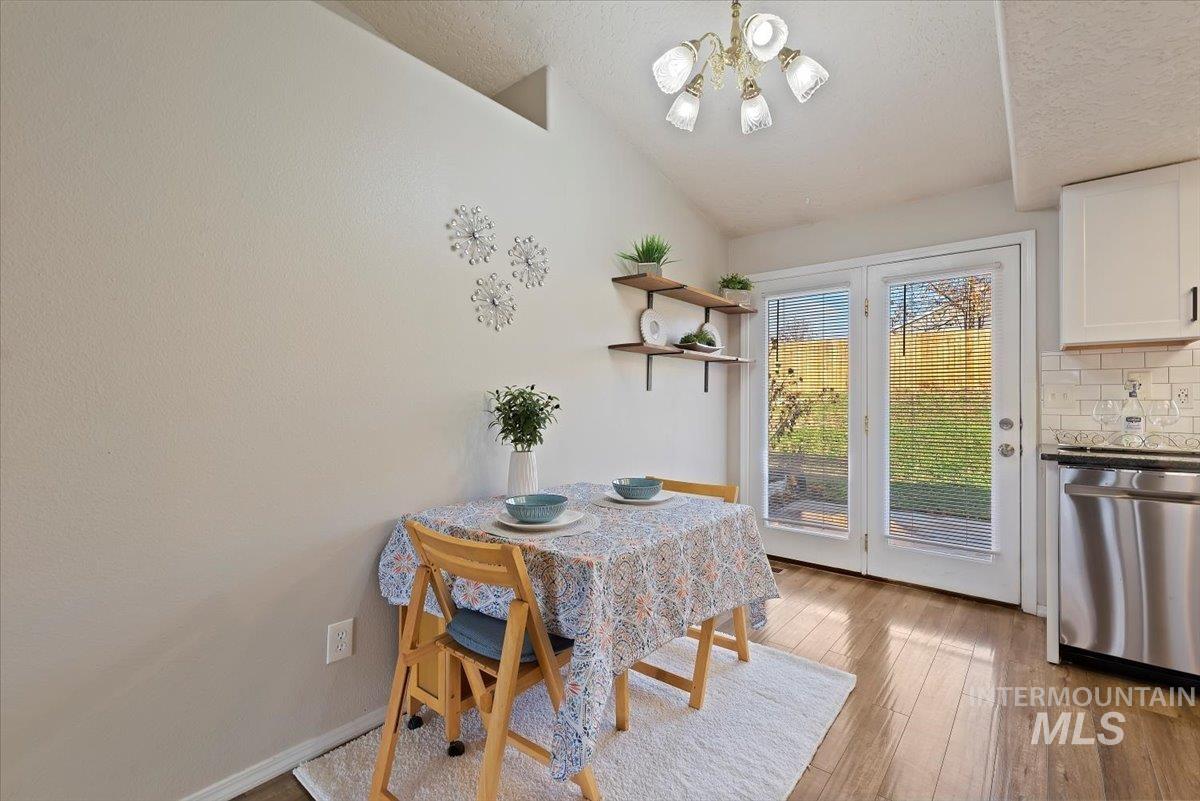 Dining area featuring light wood-style flooring, a chandelier, a textured ceiling, and lofted ceiling