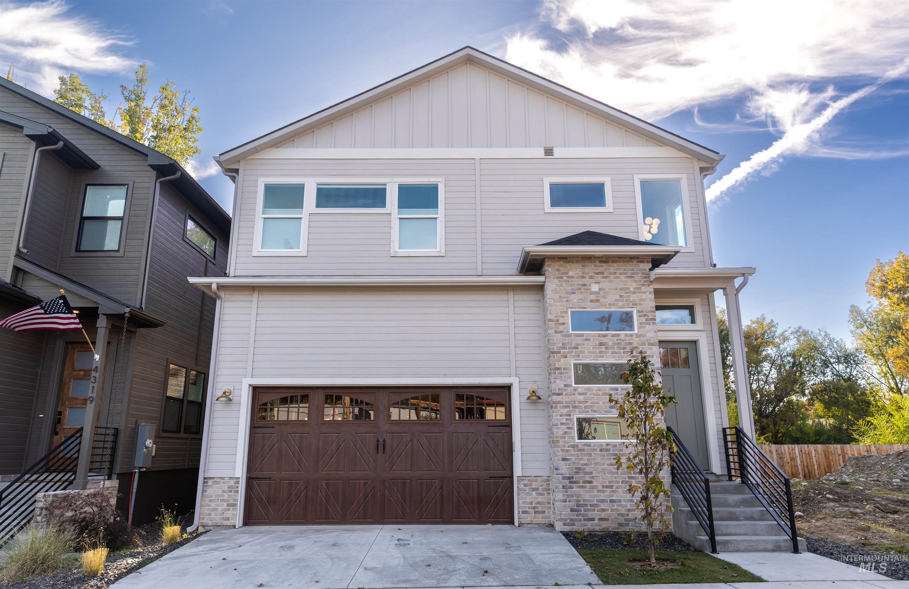 View of front of house with board and batten siding, stone siding, concrete driveway, and an attached garage