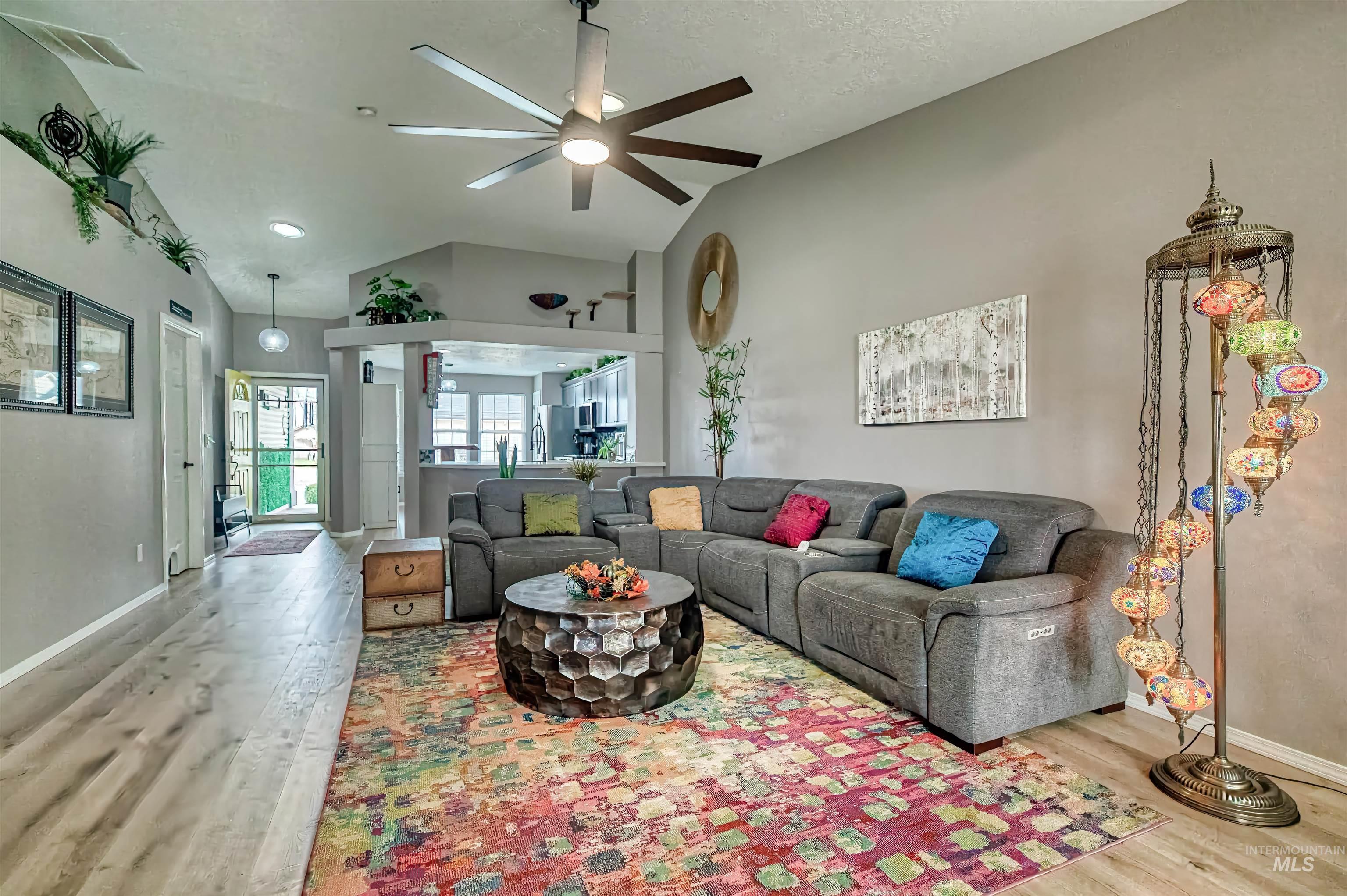Living room featuring vaulted ceiling, light wood finished floors, and a ceiling fan