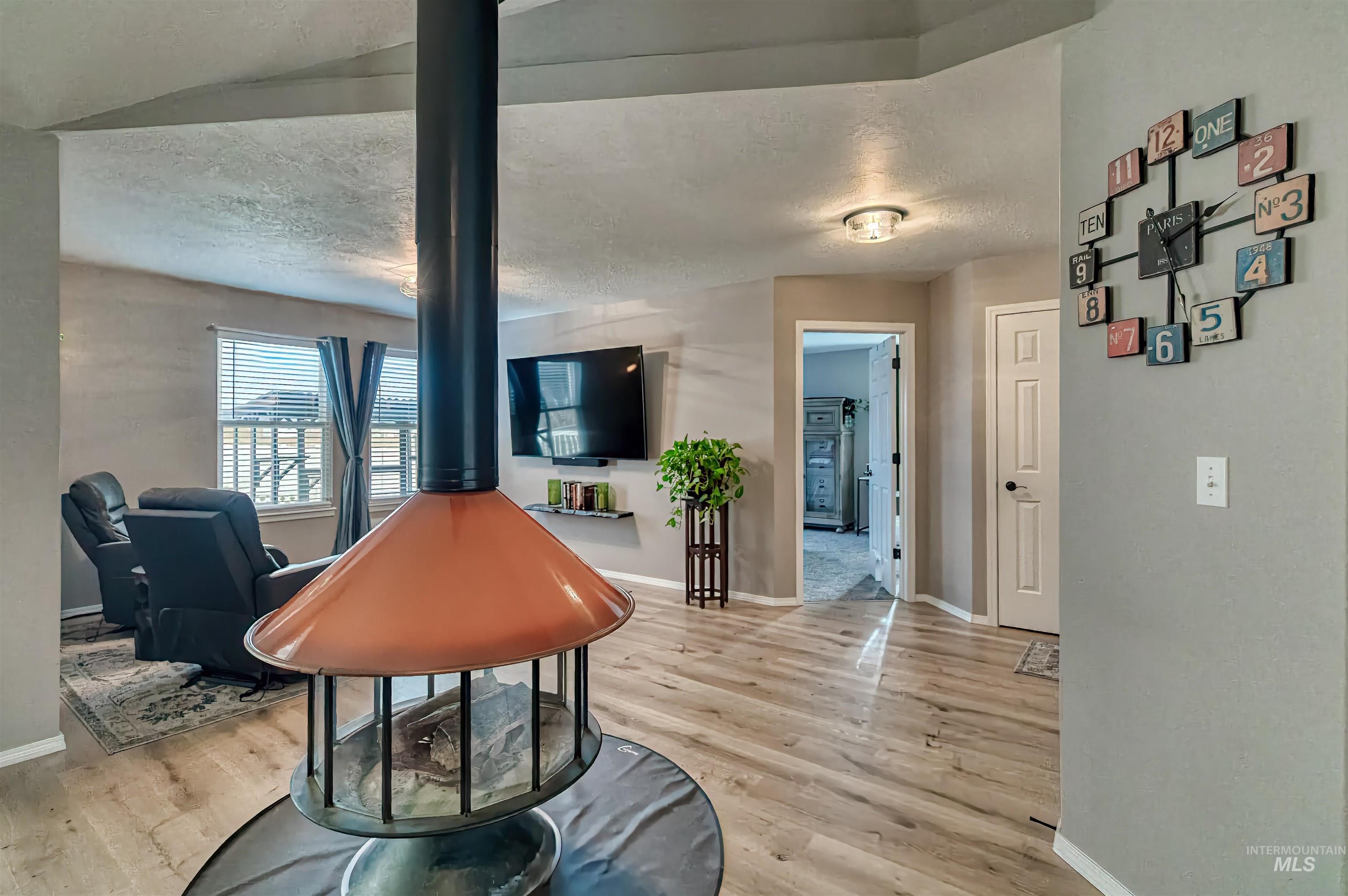 Living area featuring a textured ceiling, a wood stove, and light wood-style flooring