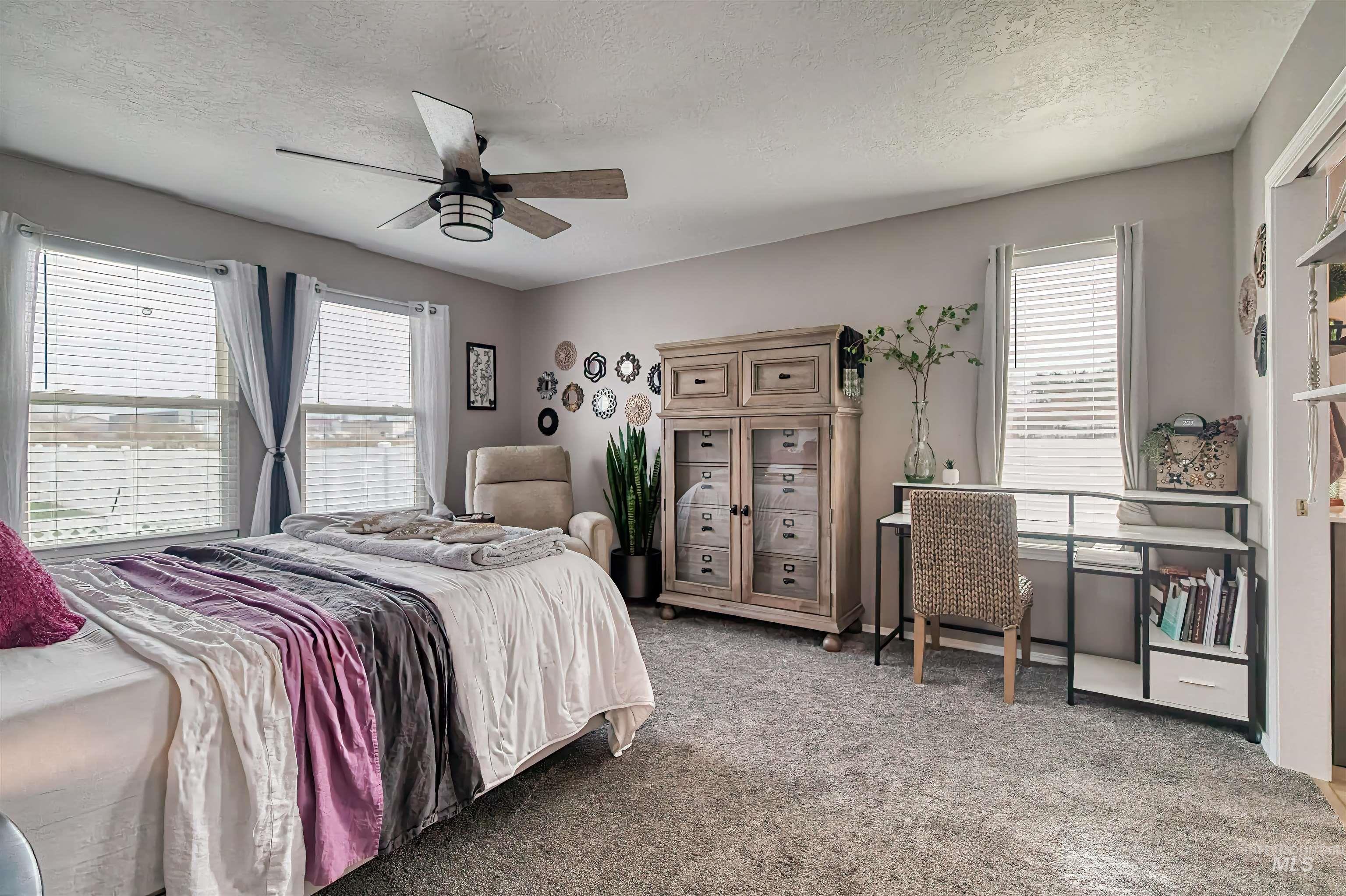 Carpeted bedroom featuring a textured ceiling and a ceiling fan