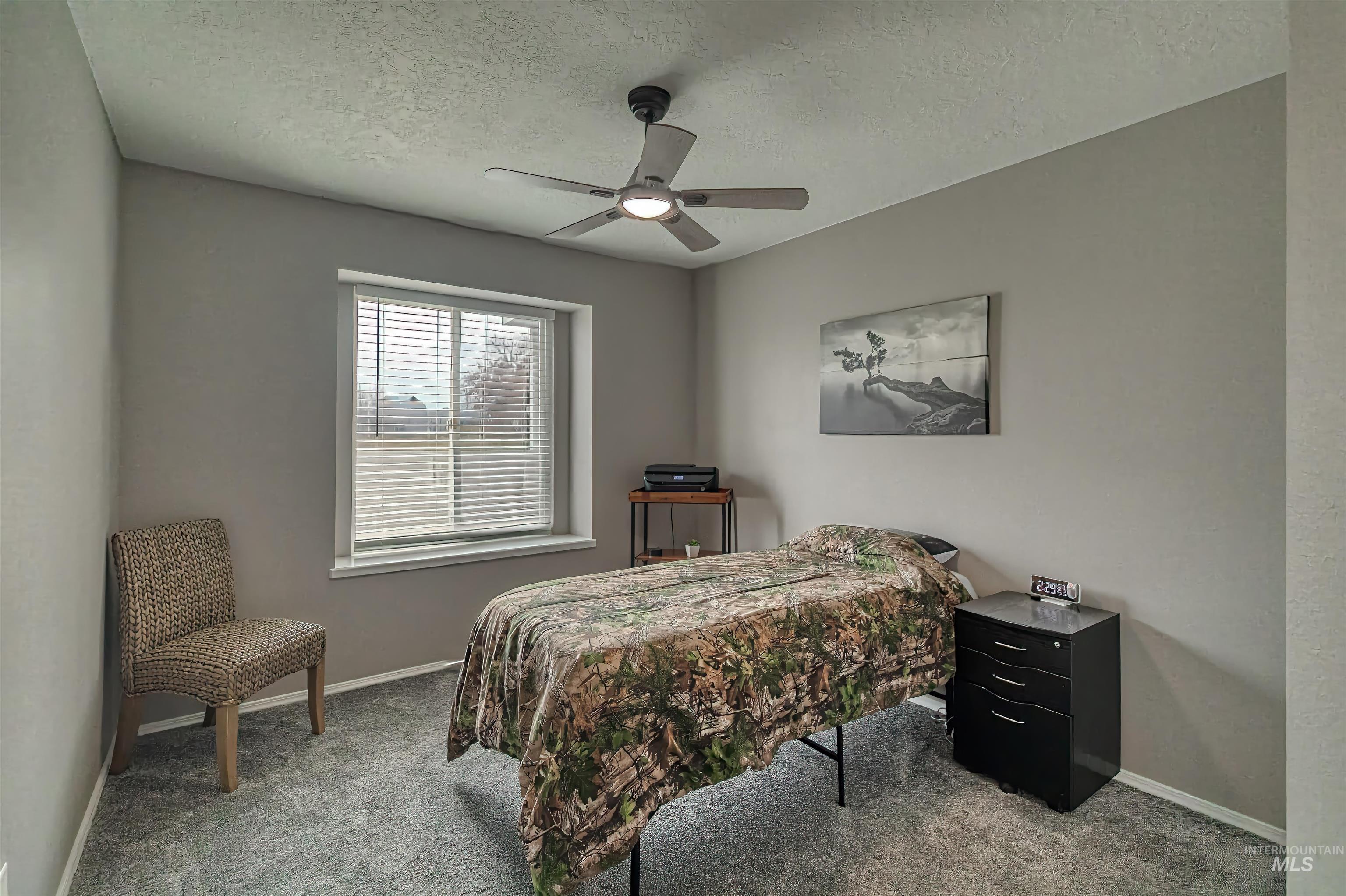 Carpeted bedroom with a textured ceiling and ceiling fan