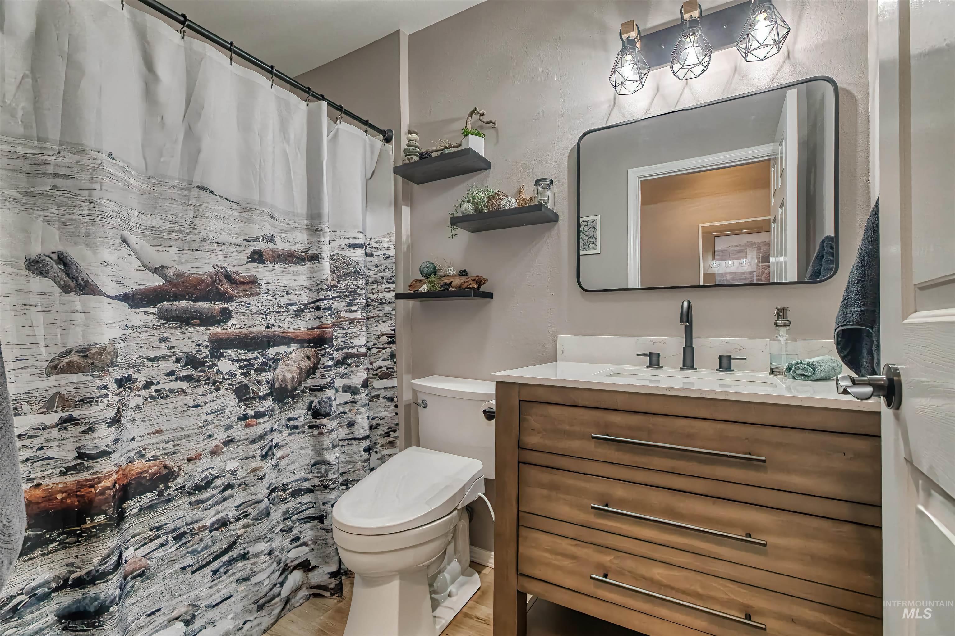 Bathroom featuring a shower with curtain, vanity, and light wood-style floors