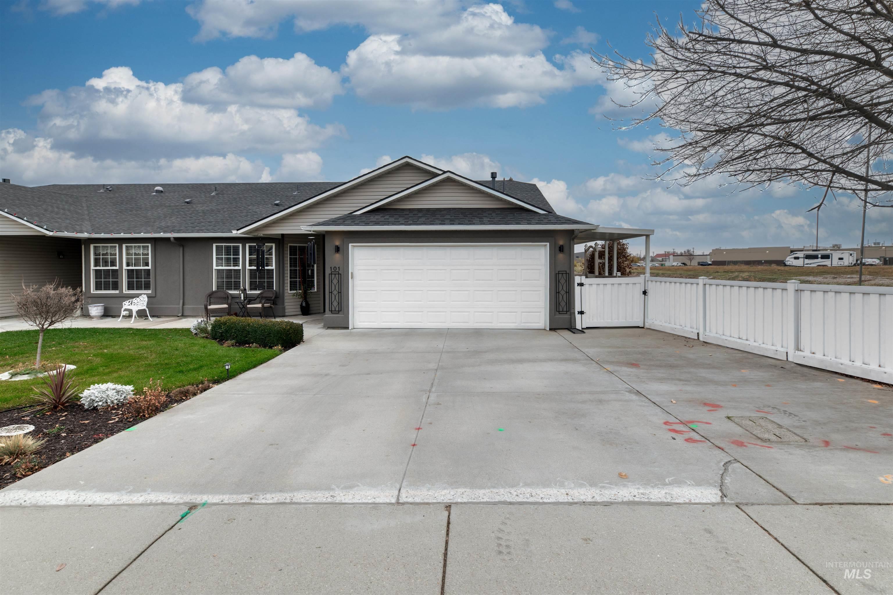 Ranch-style home with roof with shingles, driveway, a garage, a patio, and a gate
