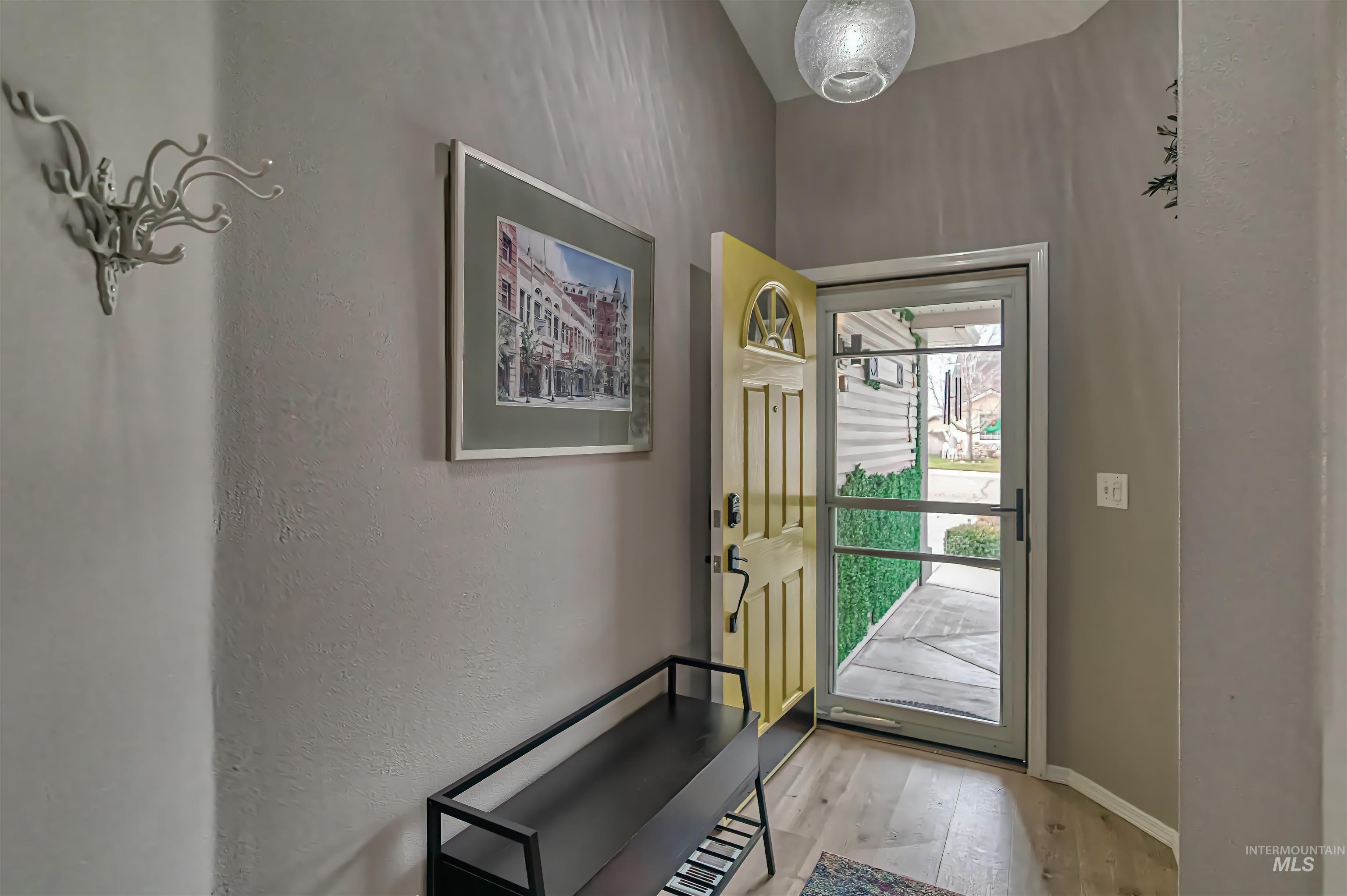 Entrance foyer with light wood-type flooring and a textured wall