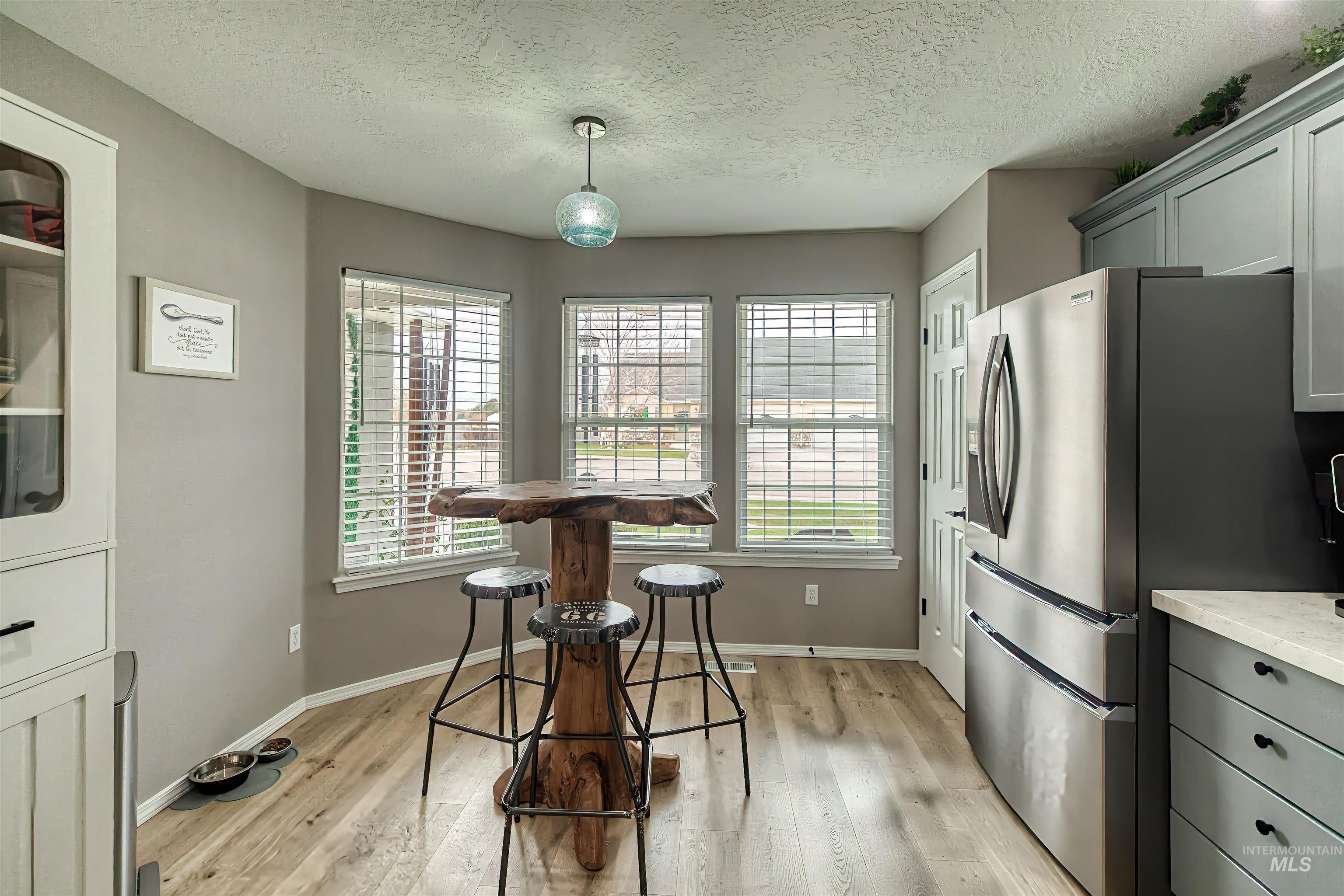 Kitchen with healthy amount of natural light, gray cabinets, a textured ceiling, and light wood-style floors