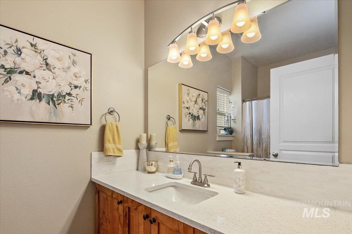 Full bath featuring vanity, a shower with curtain, backsplash, and a textured wall
