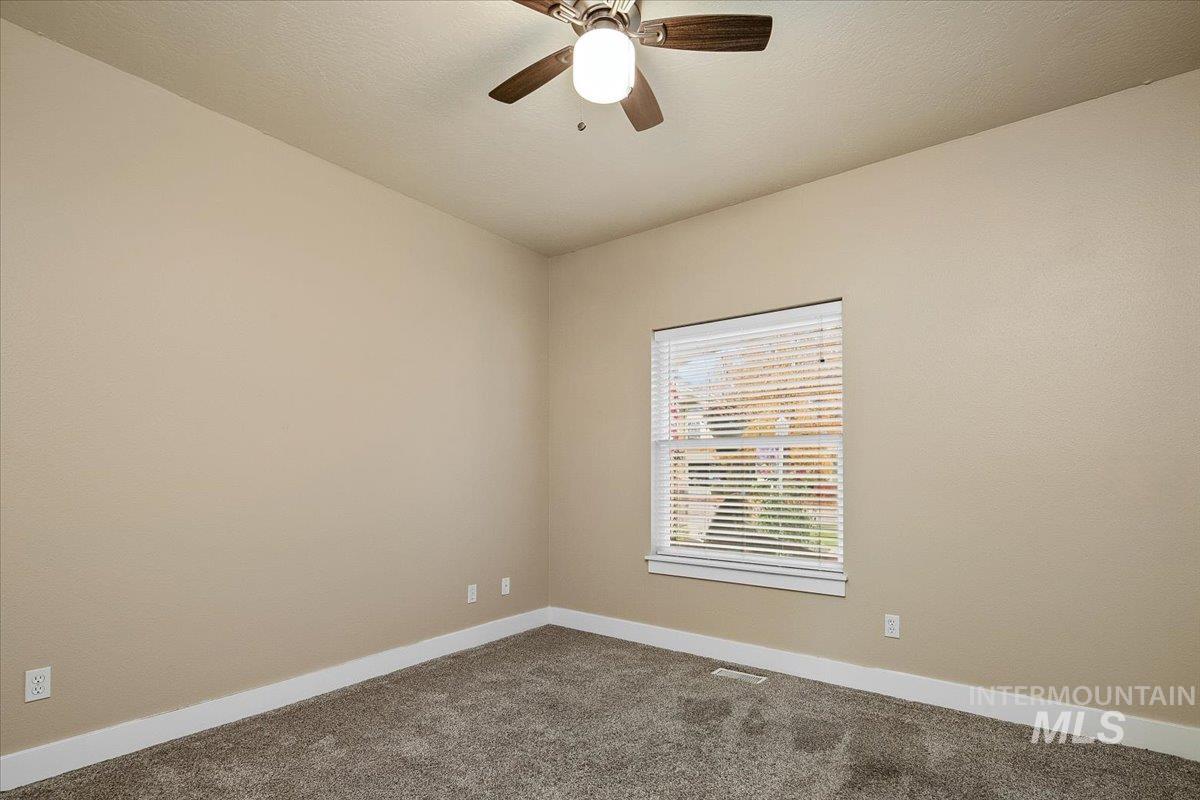 Spare room featuring carpet and ceiling fan