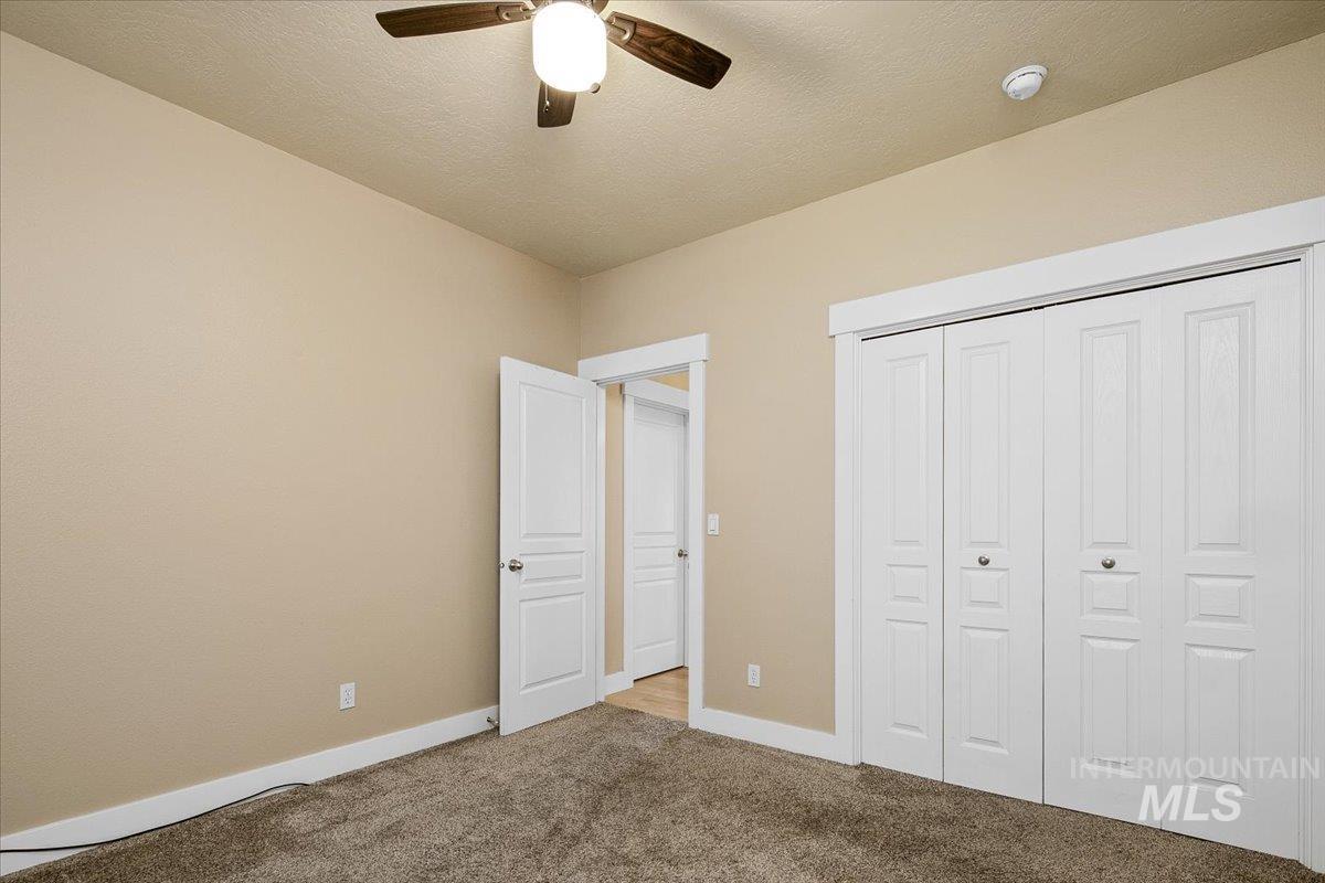 Unfurnished bedroom featuring carpet floors, a closet, ceiling fan, and a textured ceiling