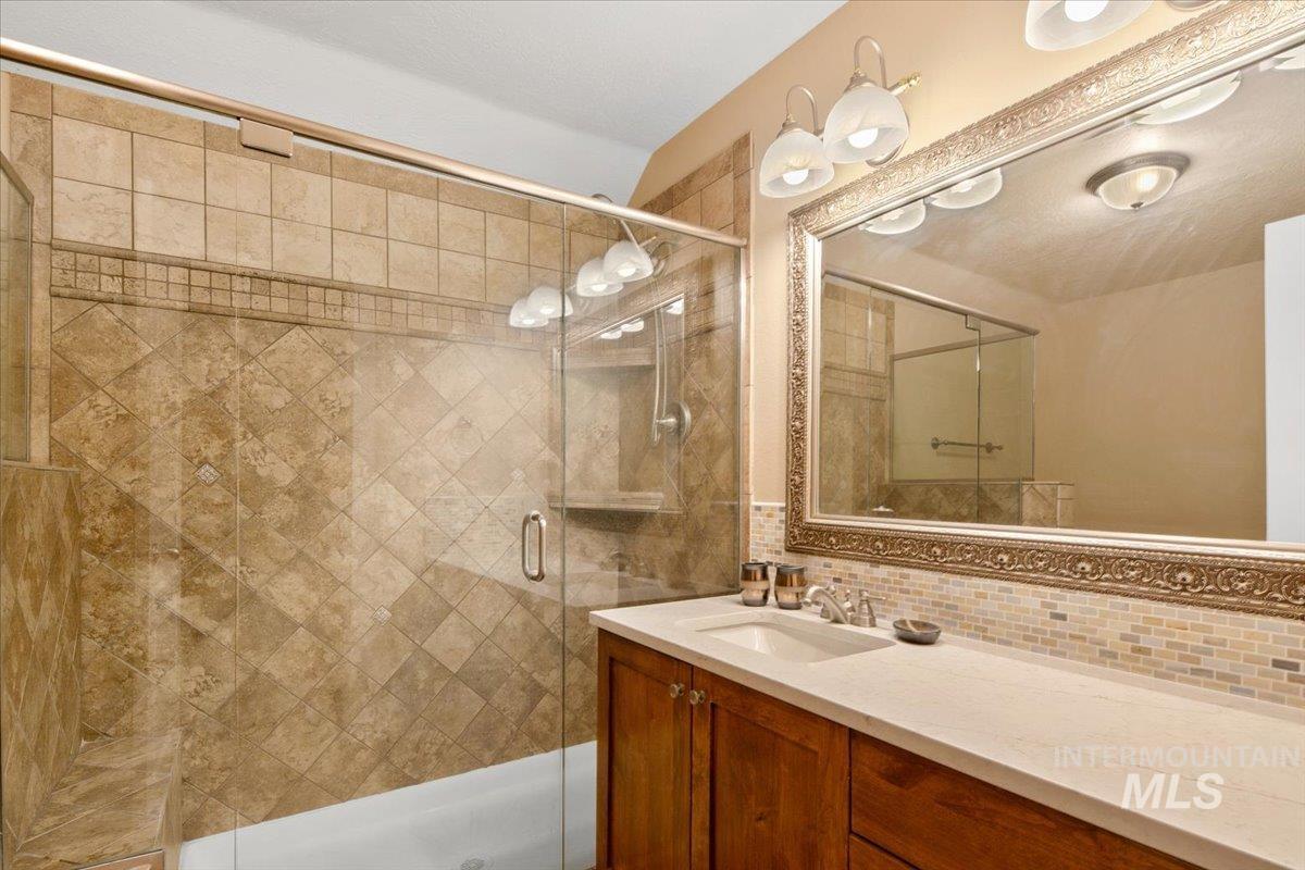 Bathroom featuring decorative backsplash, vanity, and a shower stall