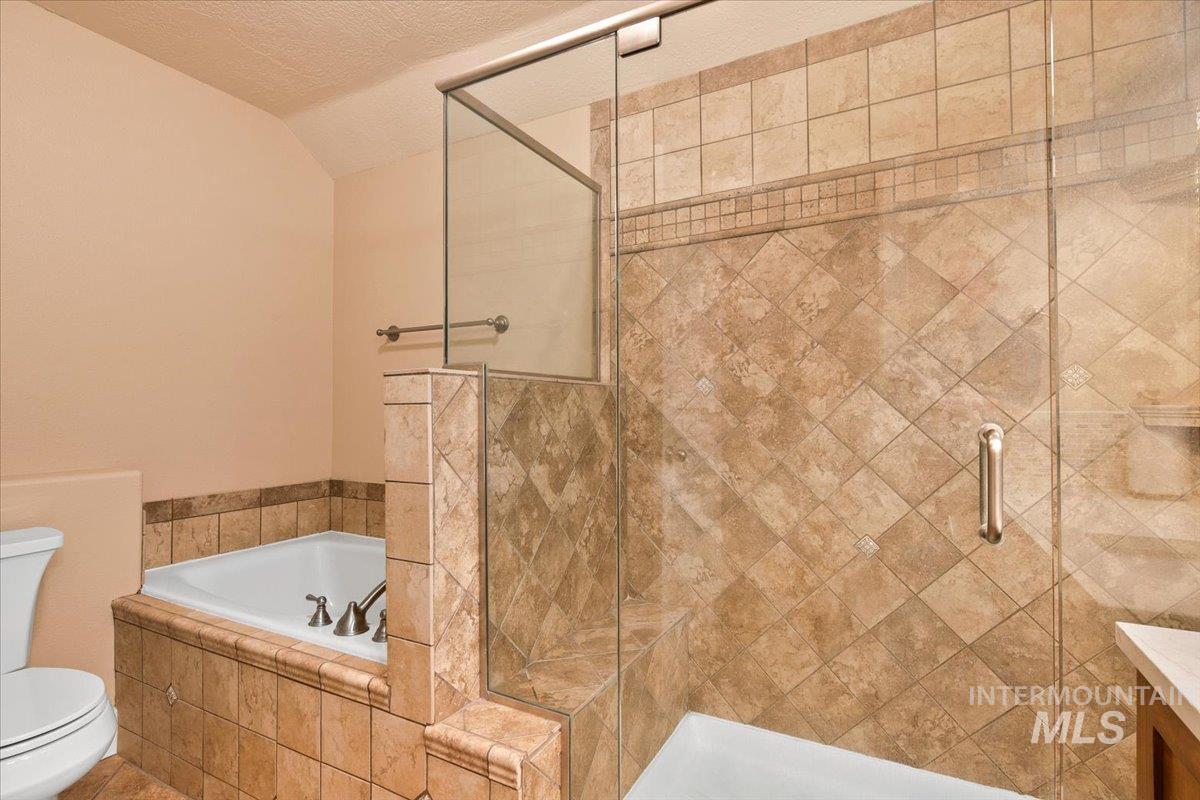 Bathroom with a stall shower, a bath, a textured ceiling, and lofted ceiling
