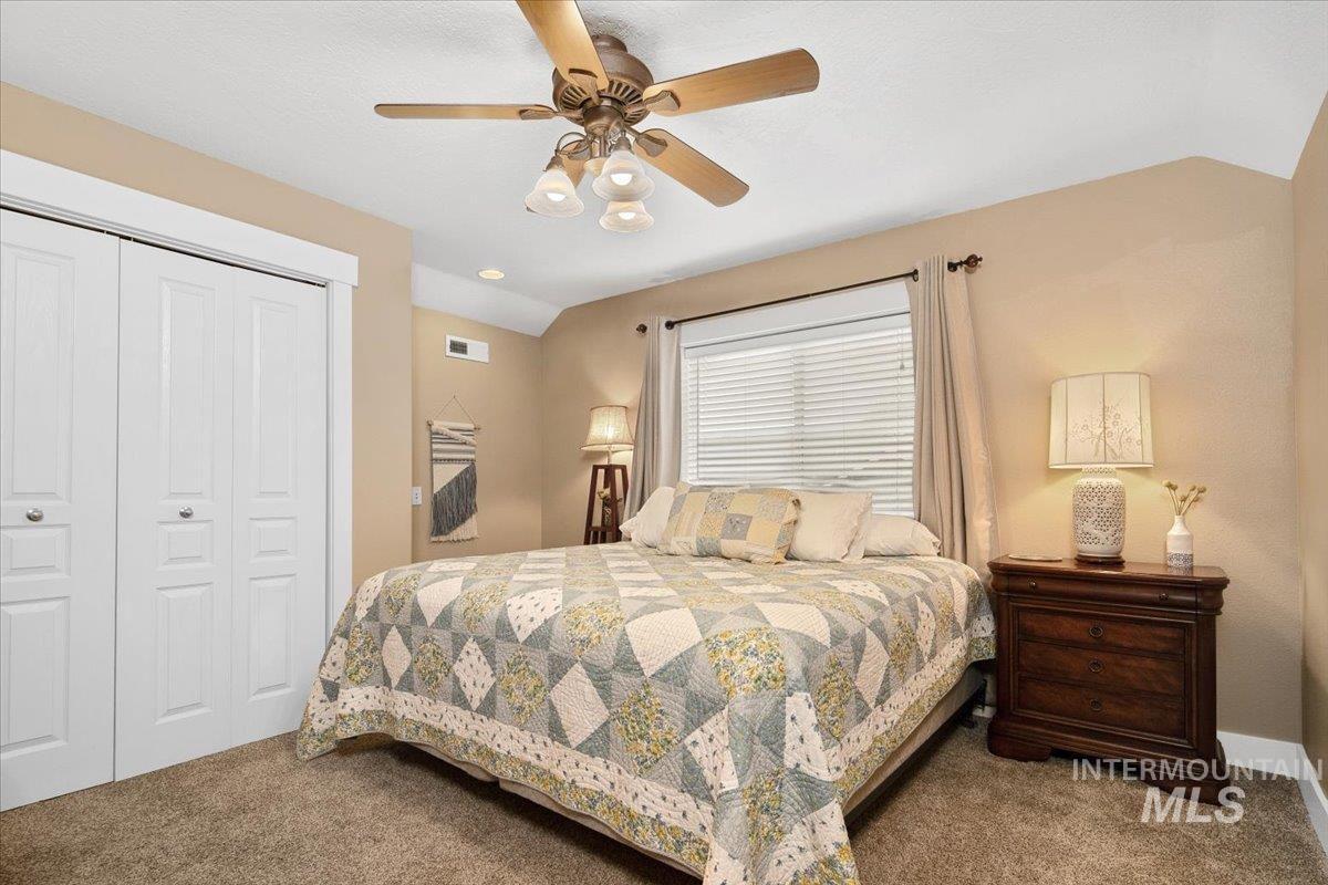 Carpeted bedroom with vaulted ceiling, a closet, and a ceiling fan
