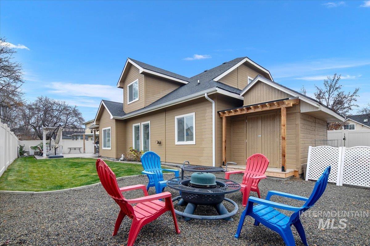 Rear view of house featuring a fenced backyard, an outdoor fire pit, a patio area, and roof with shingles