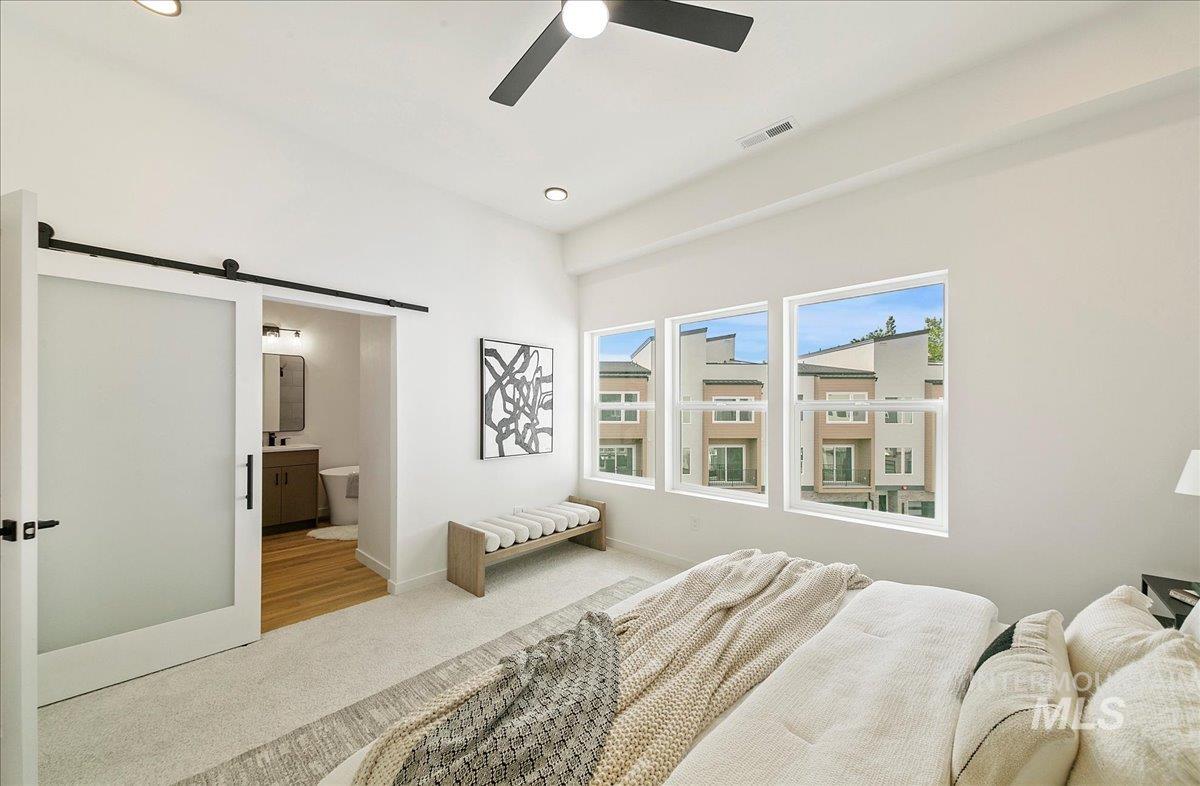 Bedroom with a barn door, recessed lighting, carpet, a ceiling fan, and connected bathroom