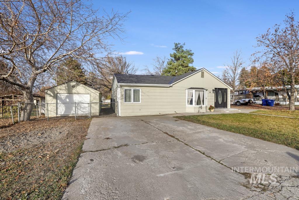 View of front facade featuring a gate, concrete driveway, and an outbuilding