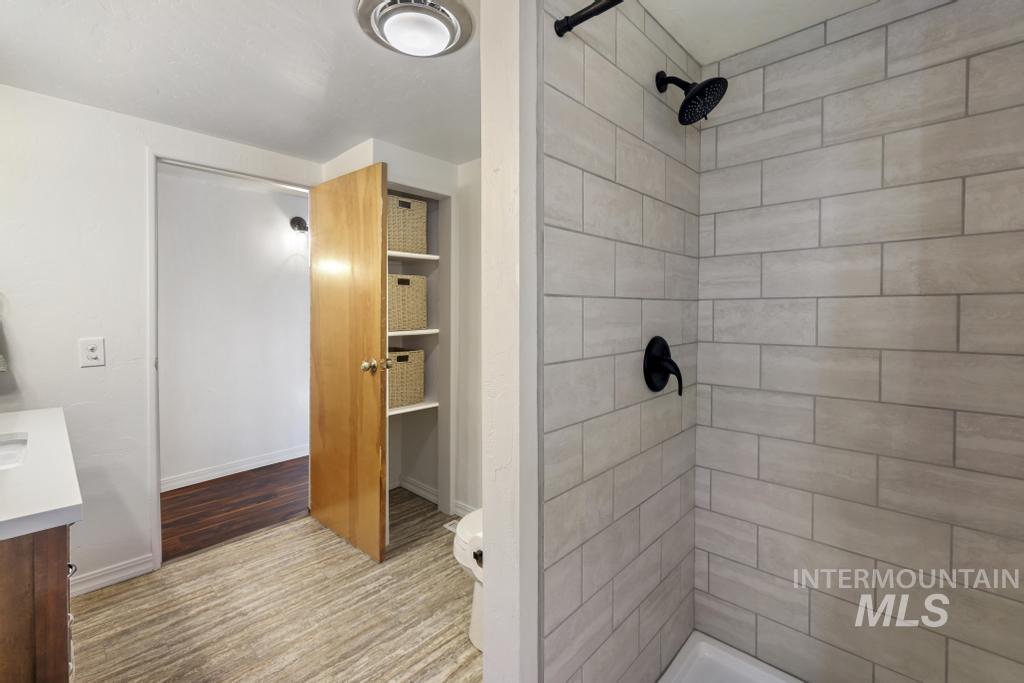 Full bathroom featuring vanity, a tile shower, and wood finished floors