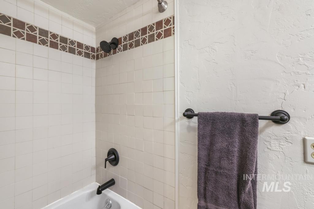 Full bathroom with bathtub / shower combination and a textured wall