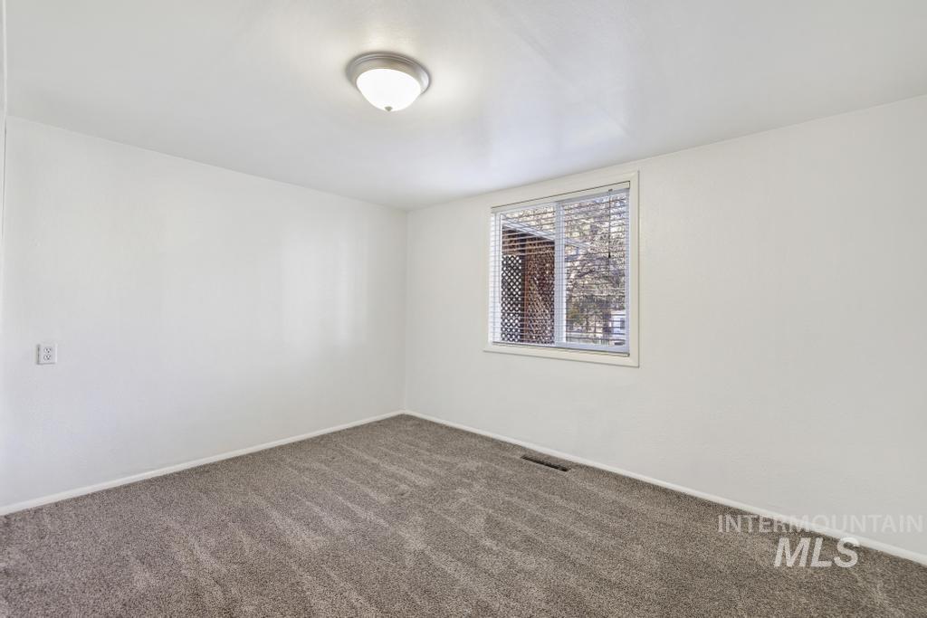 Carpeted spare room featuring baseboards