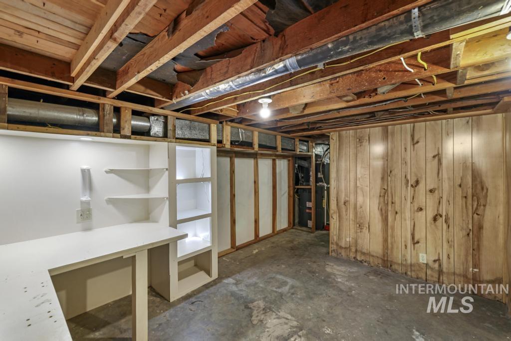 Unfinished basement with wooden walls and heating unit