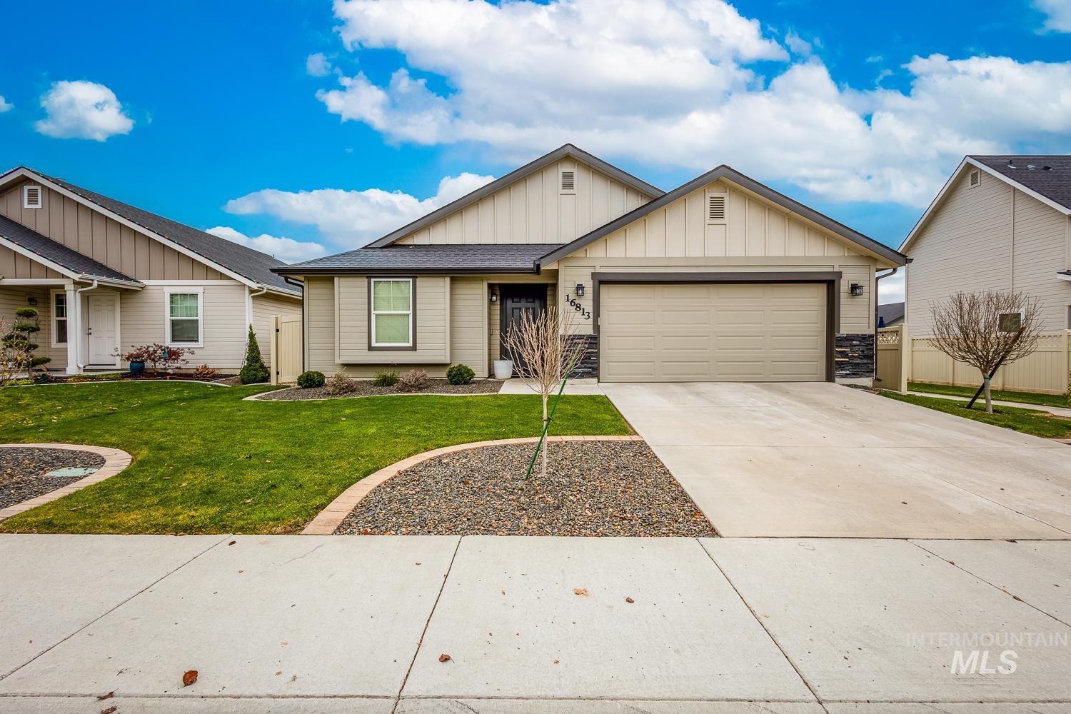 Single story home with board and batten siding, concrete driveway, a garage, and stone siding