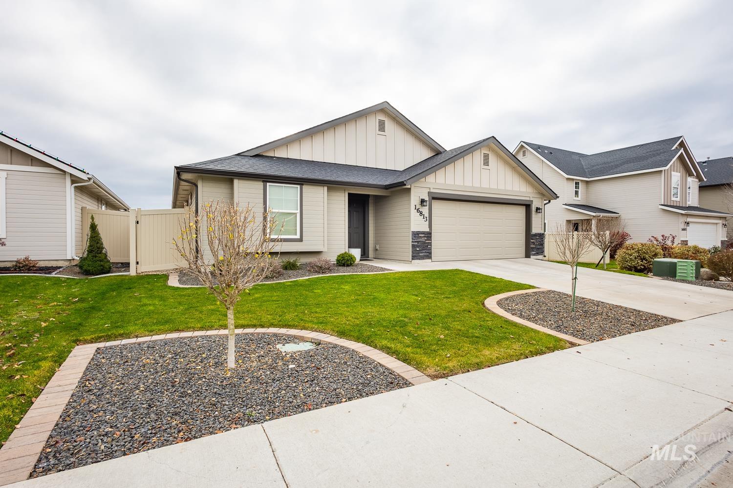View of front of house featuring board and batten siding, concrete driveway, a shingled roof, an attached garage, and stone siding