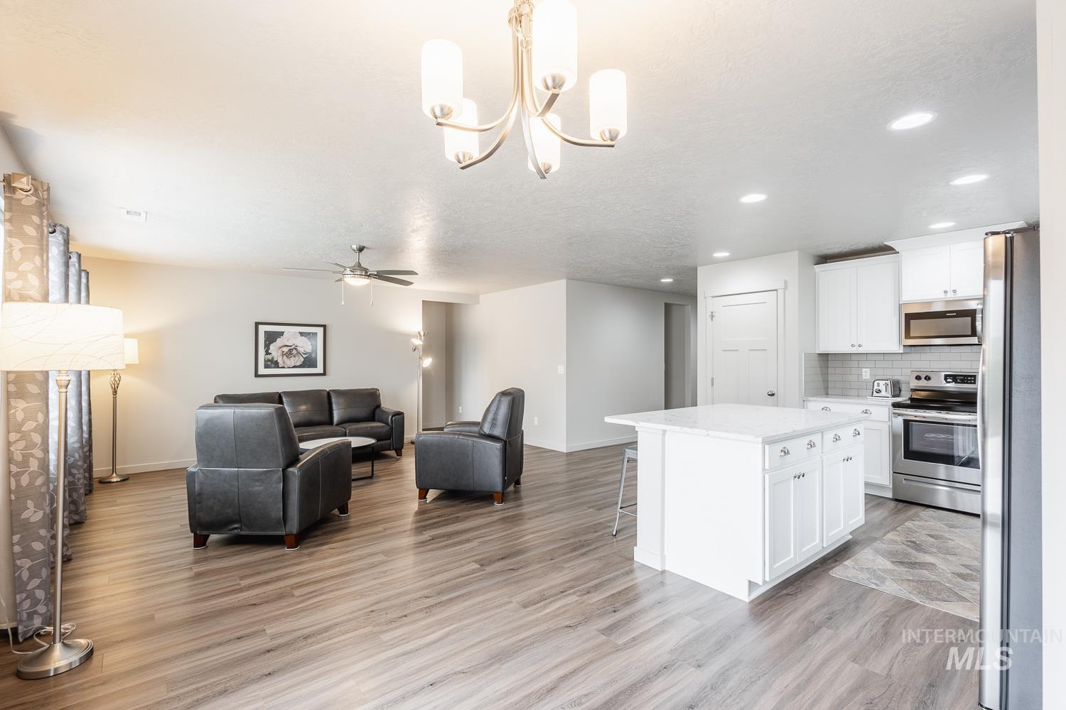 Kitchen with hanging light fixtures, a kitchen bar, stainless steel appliances, ceiling fan, and a center island