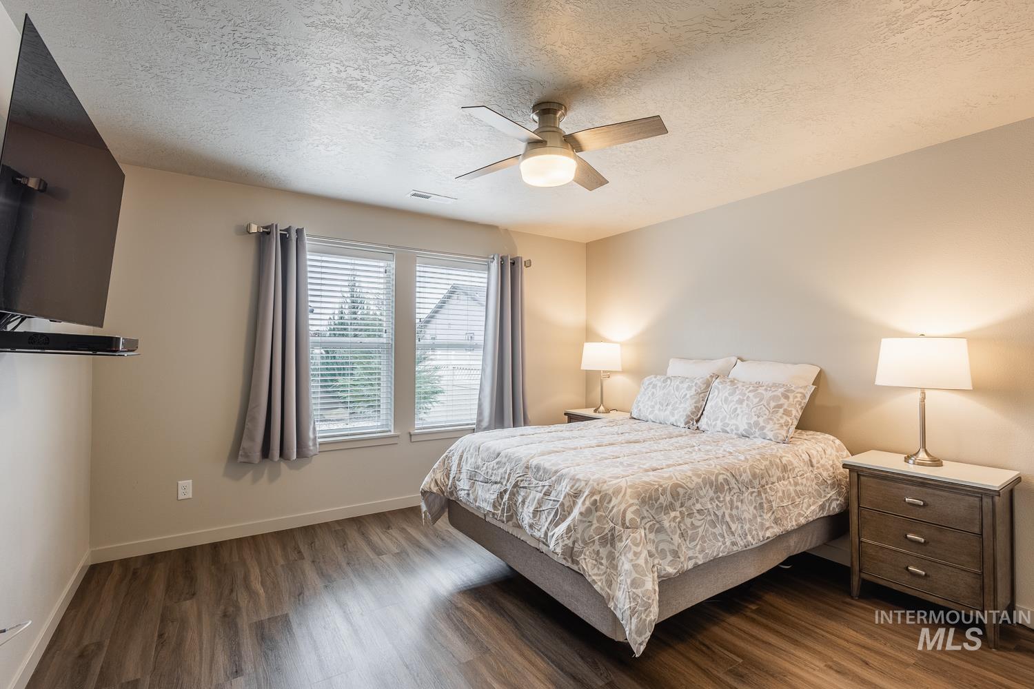 Bedroom with a textured ceiling, wood finished floors, and ceiling fan