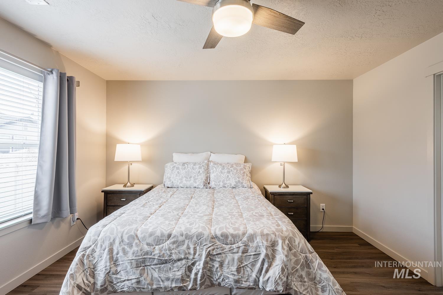 Bedroom with dark wood-style floors, a ceiling fan, and a textured ceiling
