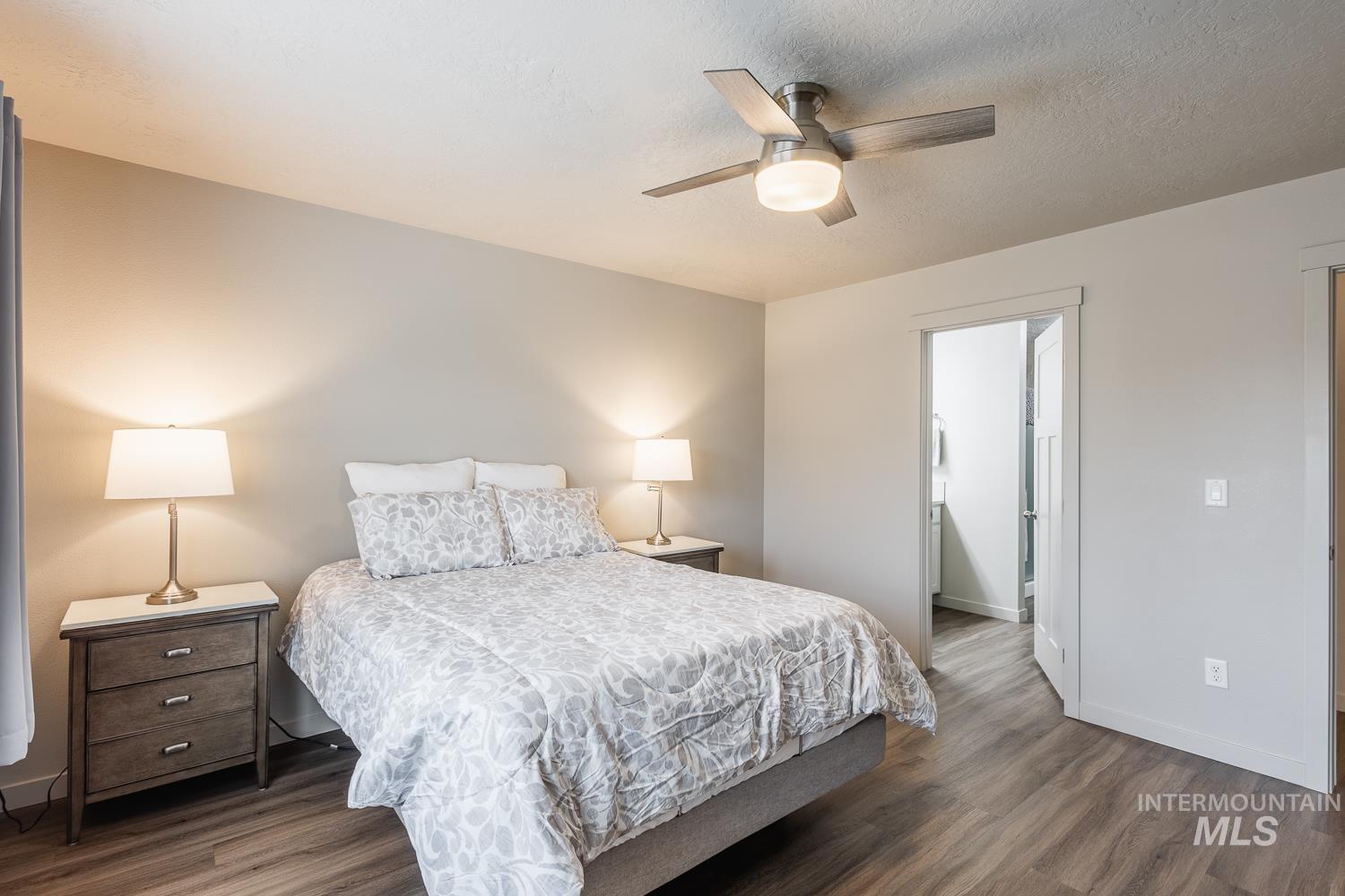 Bedroom featuring wood finished floors, ensuite bathroom, a ceiling fan, and a textured ceiling