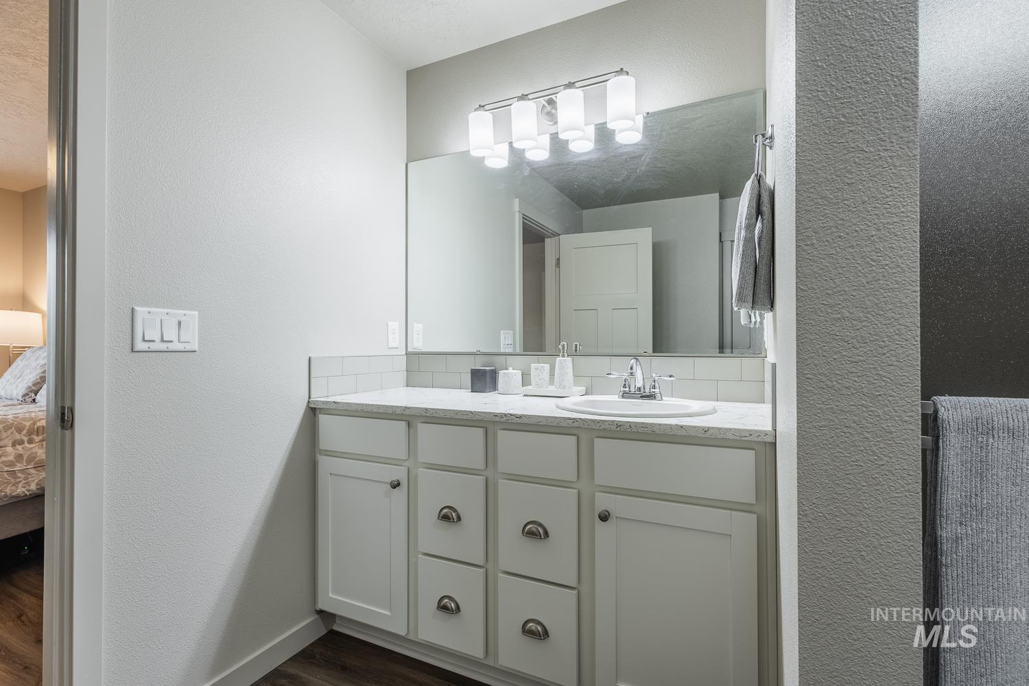 Bathroom featuring a textured wall, vanity, ensuite bathroom, and dark wood-type flooring