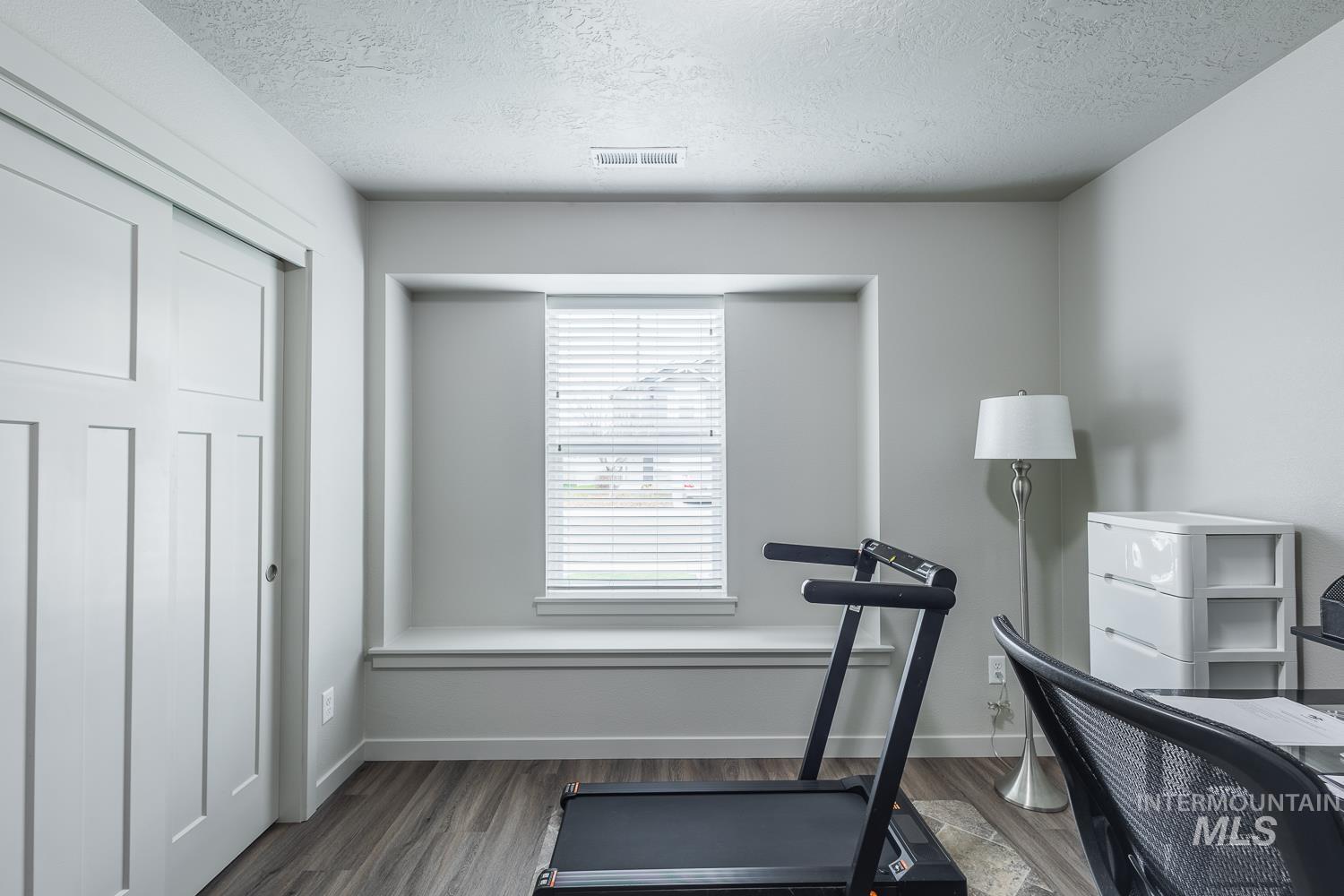 Exercise area with a textured ceiling and dark wood finished floors