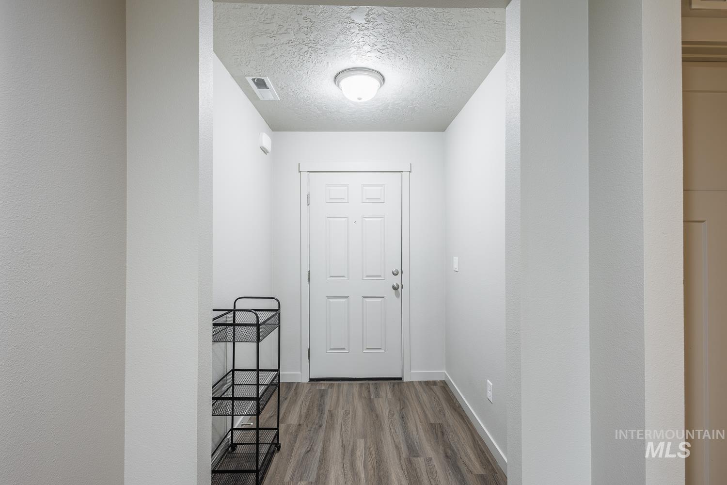 Entryway with a textured ceiling and wood finished floors