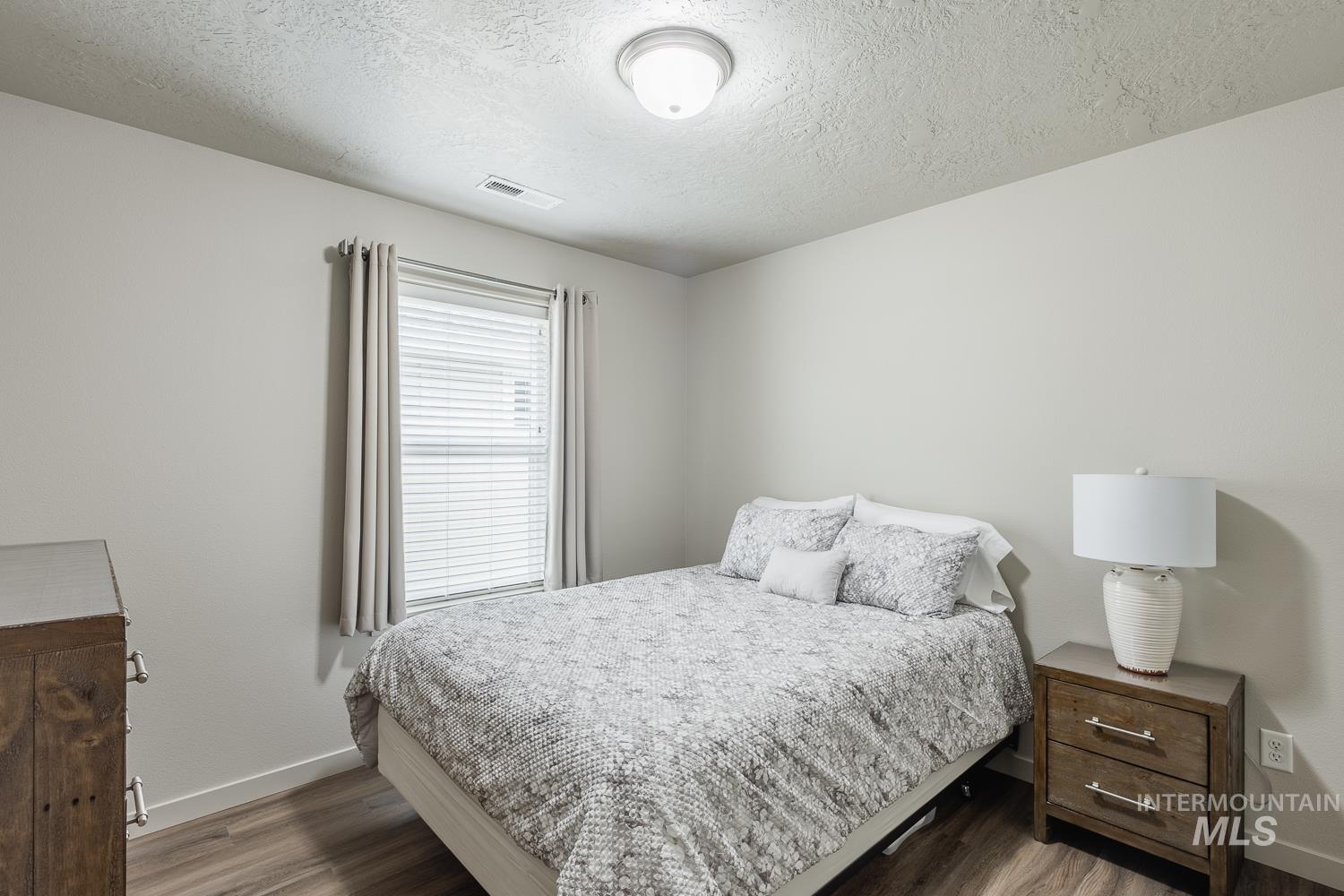 Bedroom with a textured ceiling and wood finished floors