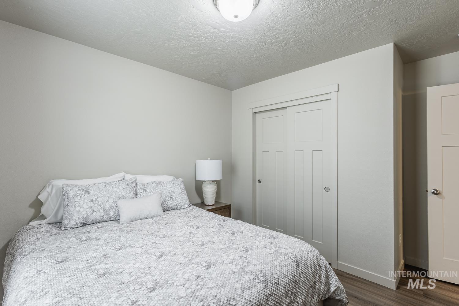 Bedroom with a textured ceiling, a closet, and dark wood-style flooring