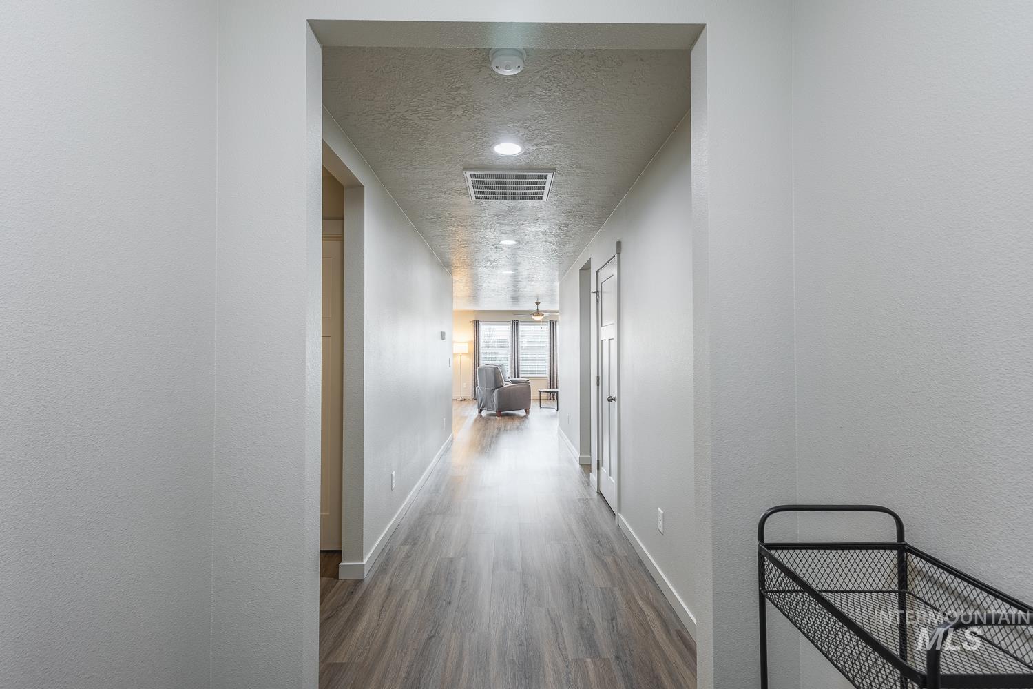 Hallway with a textured ceiling and wood finished floors
