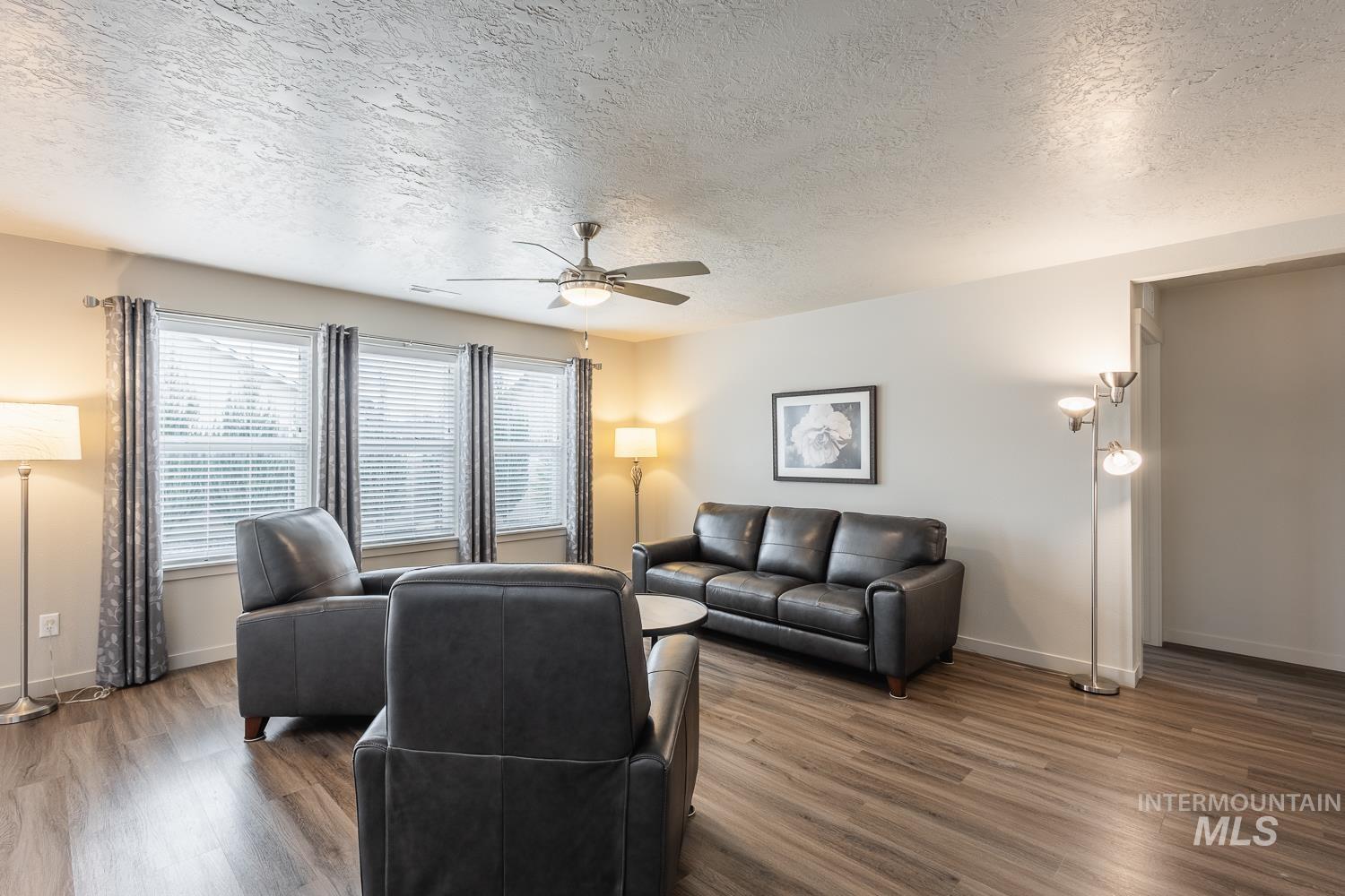 Living area with a textured ceiling, wood finished floors, and ceiling fan