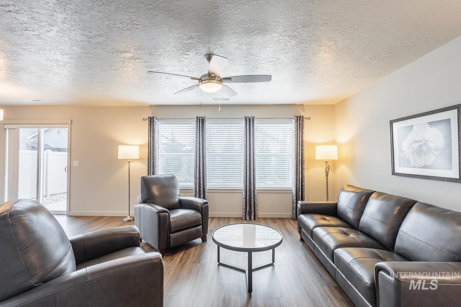 Living room featuring a textured ceiling, ceiling fan, and wood finished floors