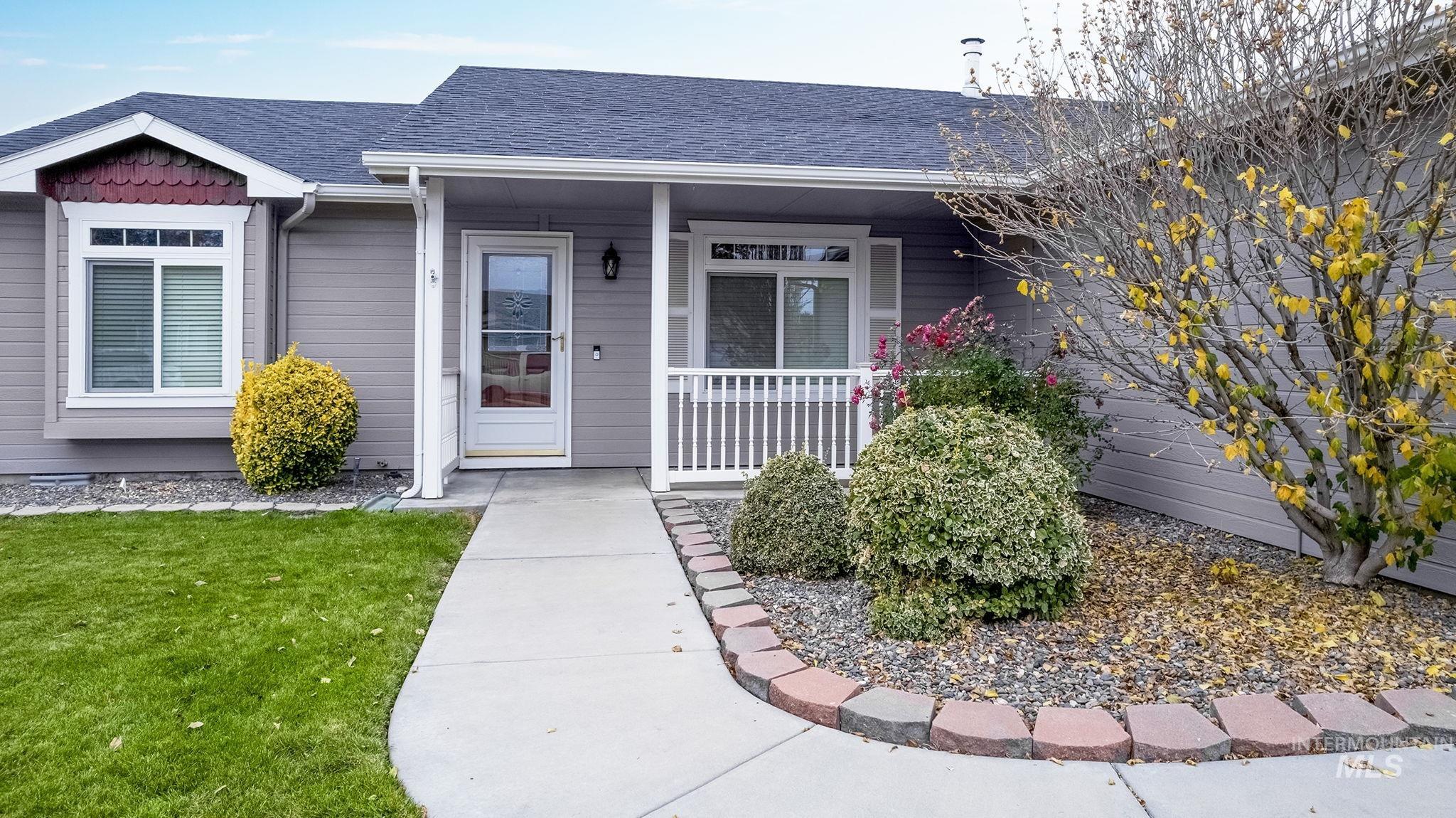 View of exterior entry featuring a shingled roof, a porch, and a yard
