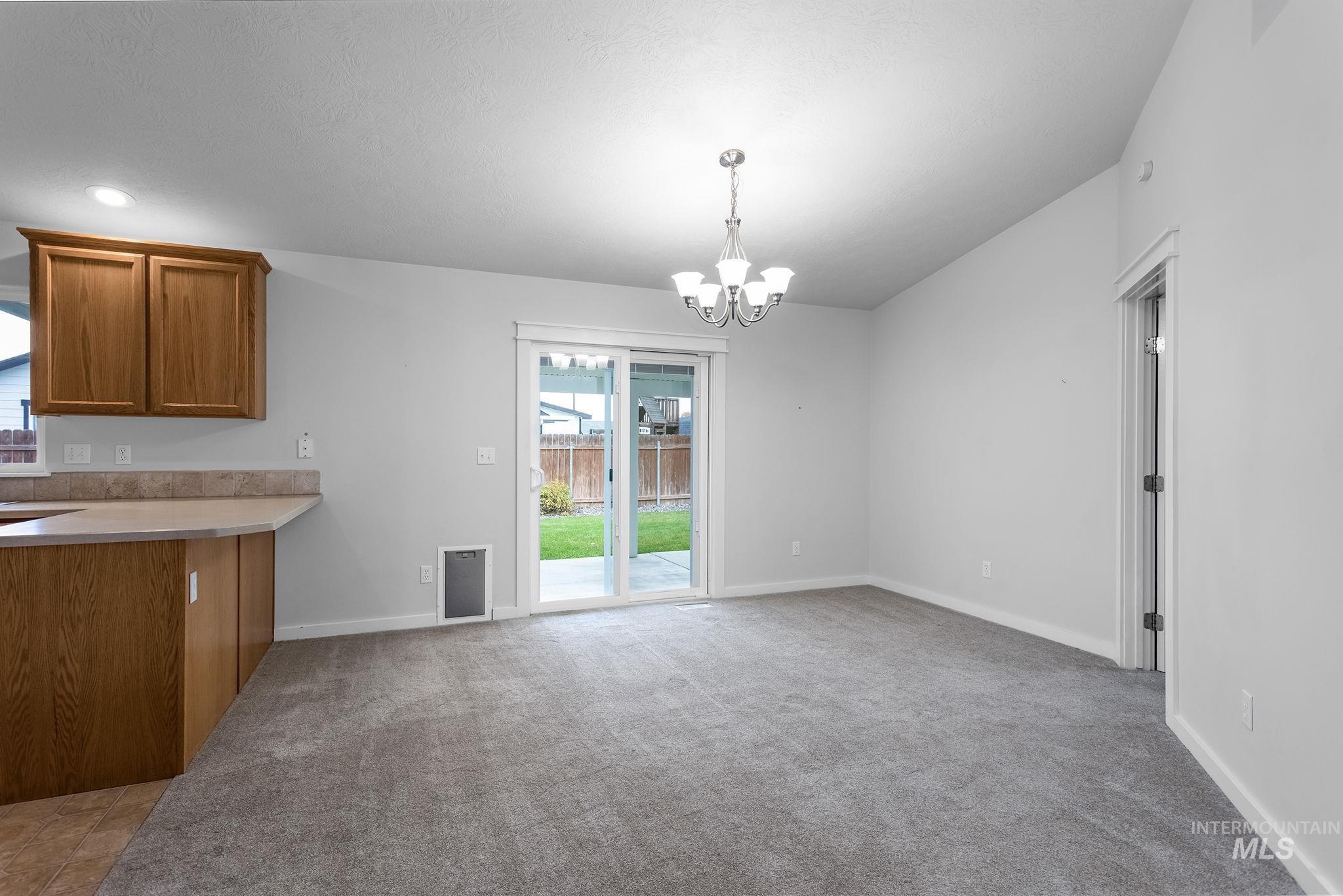 Unfurnished dining area featuring a chandelier and light carpet