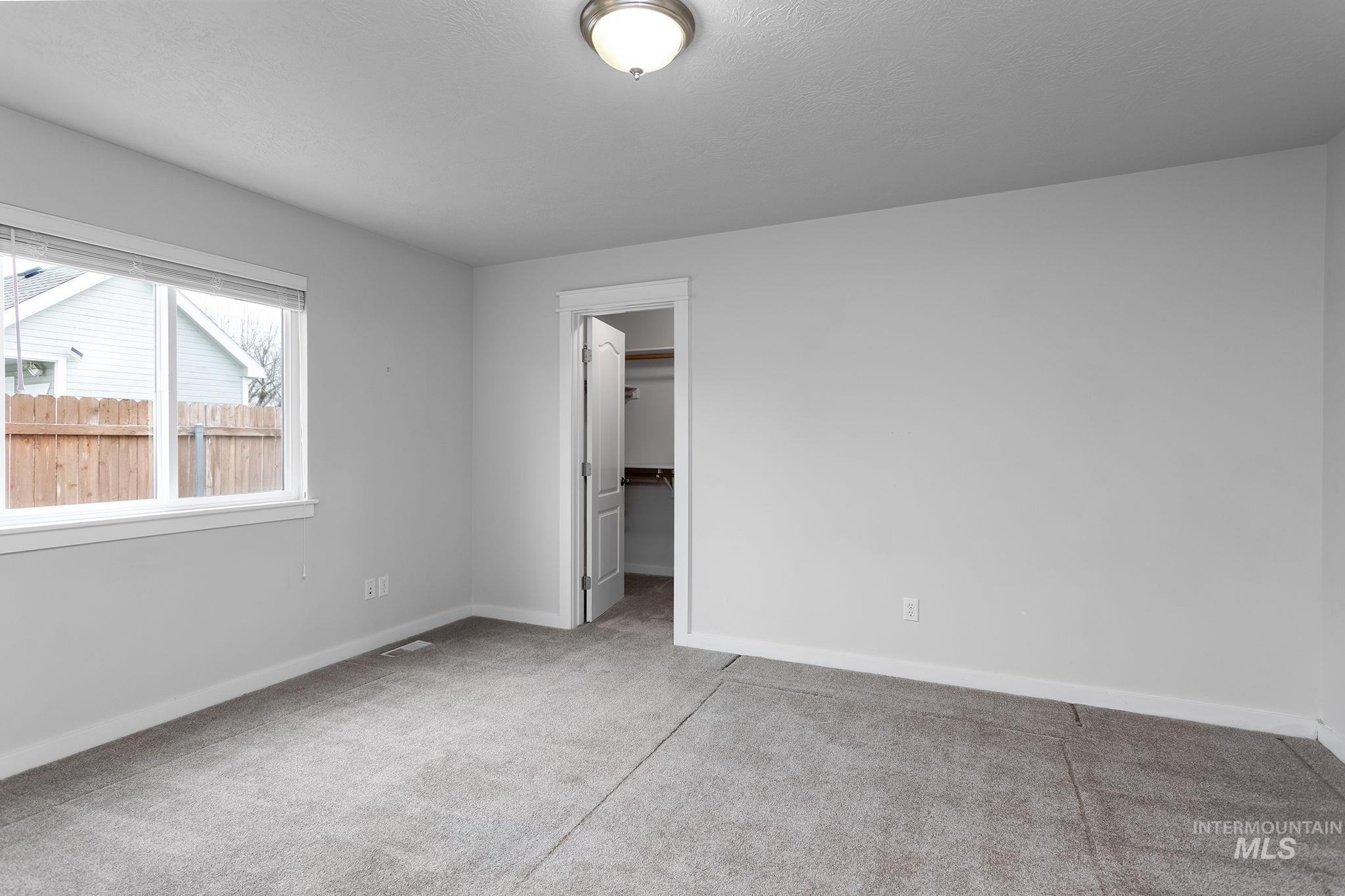 Unfurnished bedroom with a spacious closet and light colored carpet