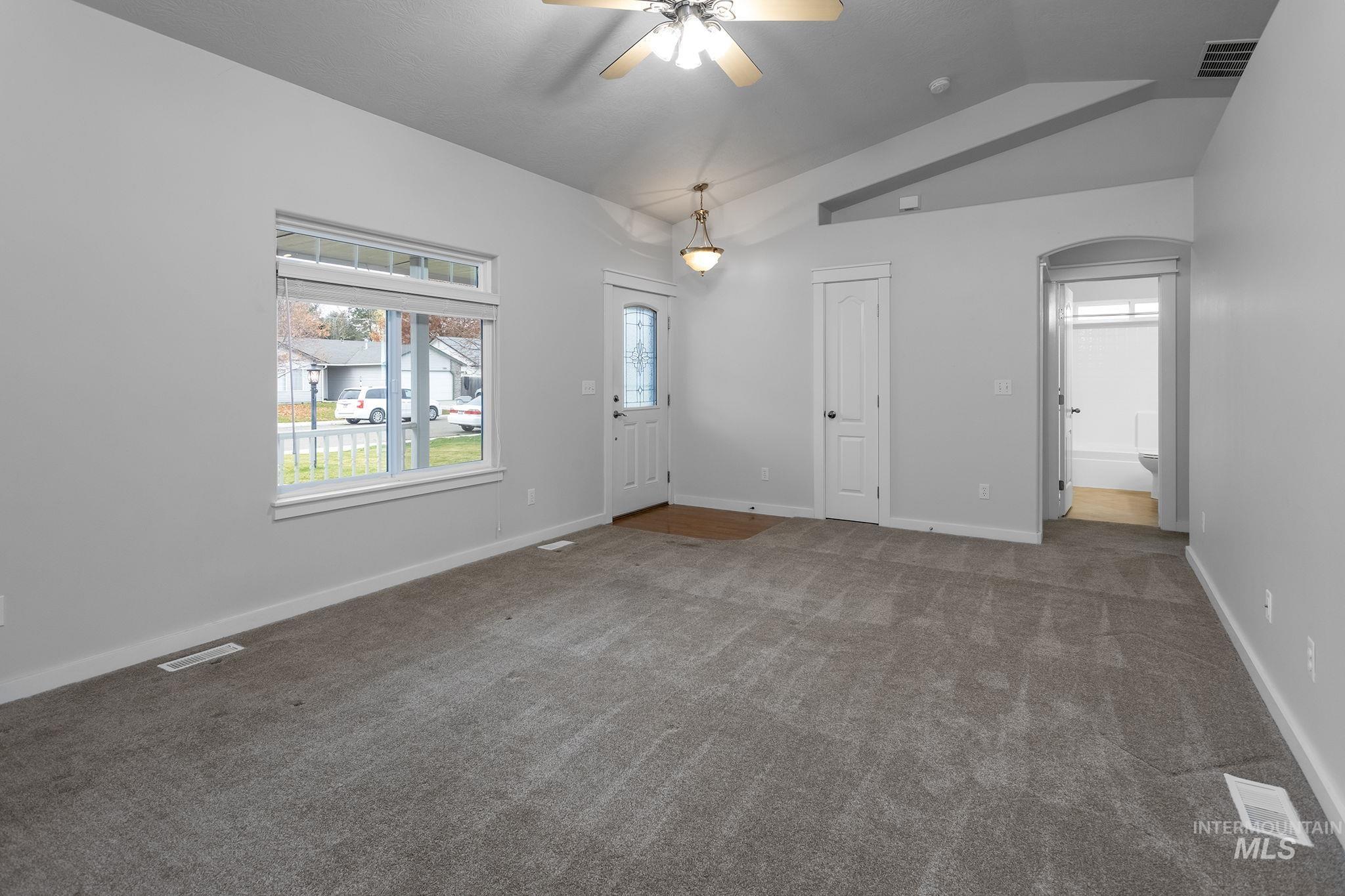 Carpeted foyer with lofted ceiling, a ceiling fan, and arched walkways
