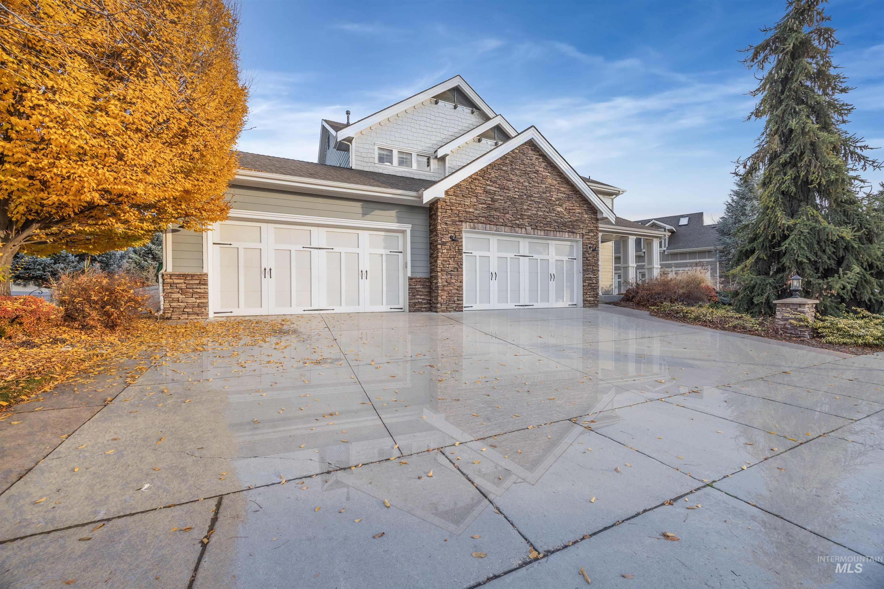 View of property exterior with stone siding, driveway, and a garage