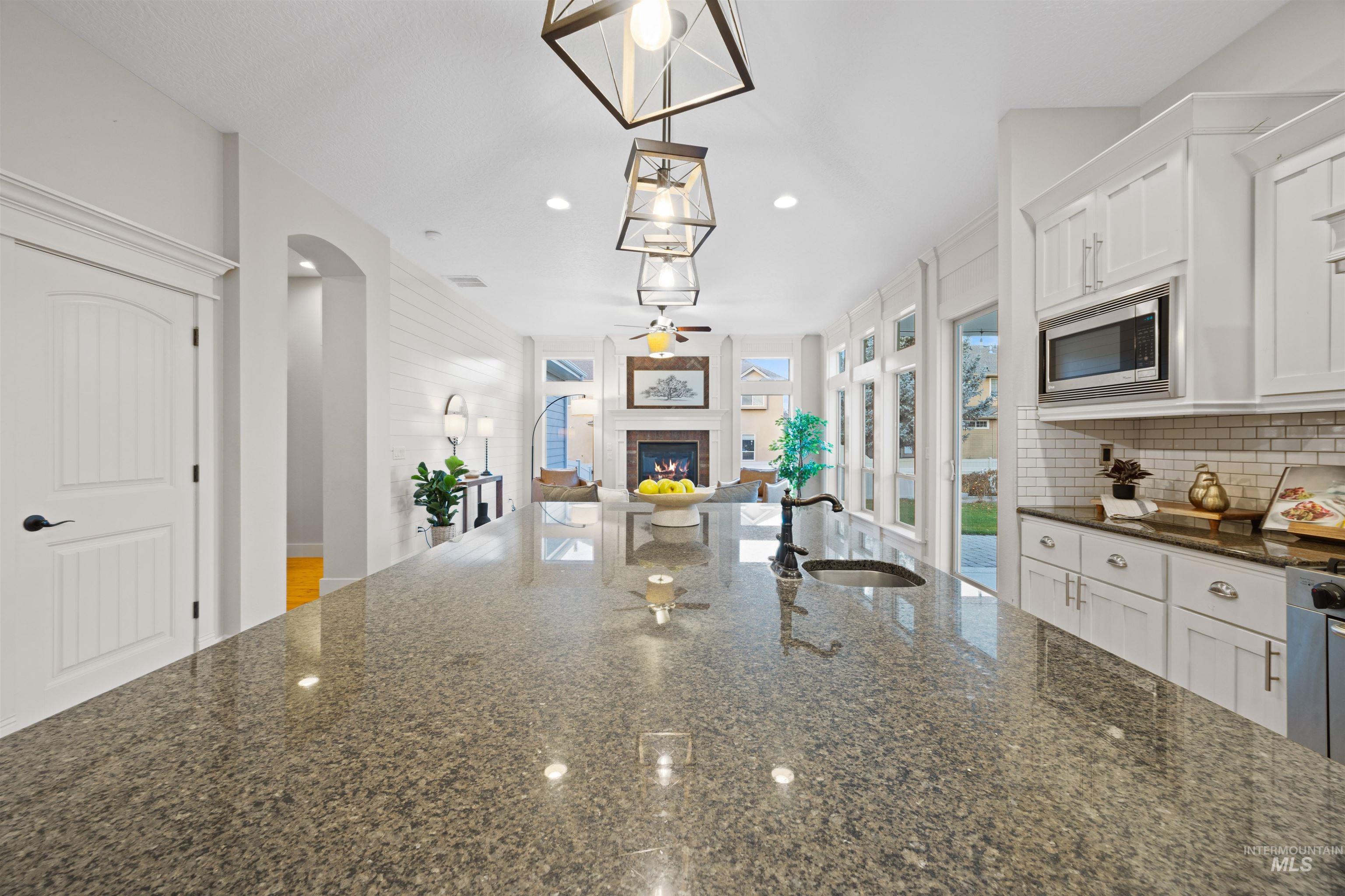 Kitchen with dark stone counters, open floor plan, white cabinetry, recessed lighting, and hanging light fixtures