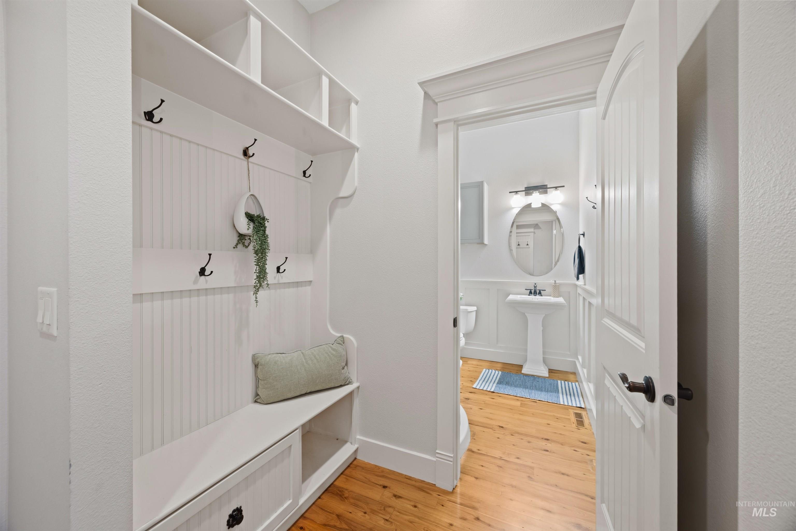Mudroom with light wood-style floors, wainscoting, and a decorative wall