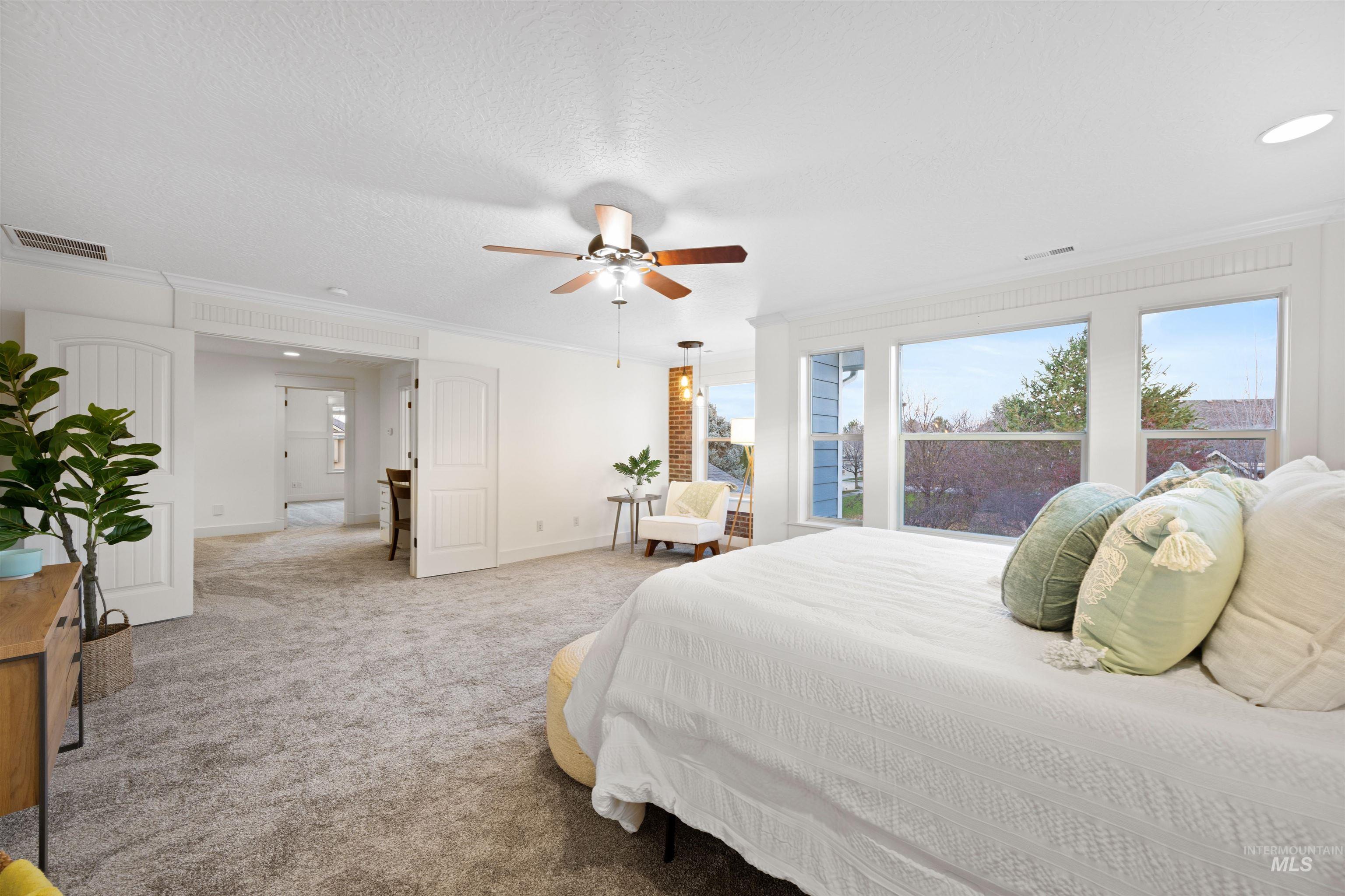 Carpeted bedroom featuring ornamental molding, a ceiling fan, and a textured ceiling