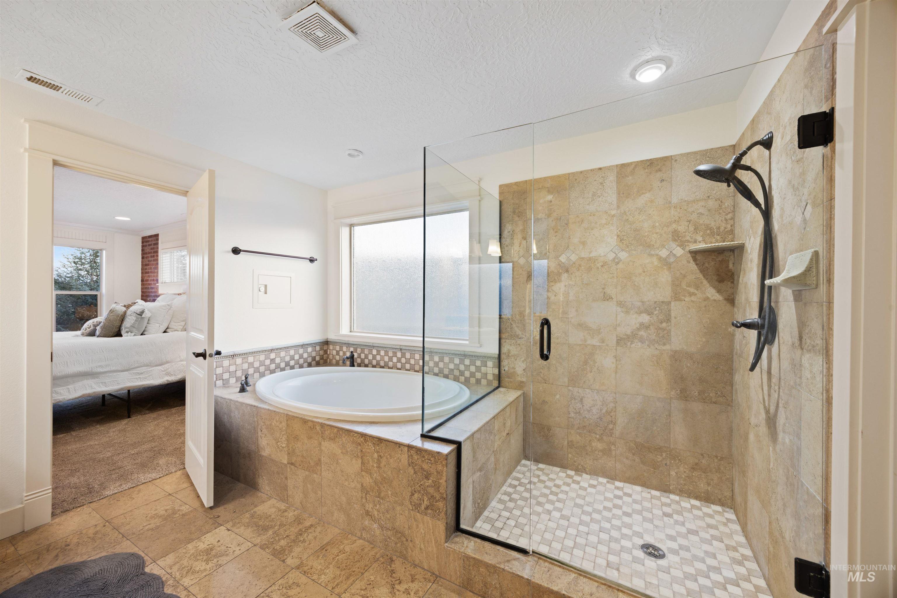 Ensuite bathroom with a stall shower, a garden tub, and a textured ceiling